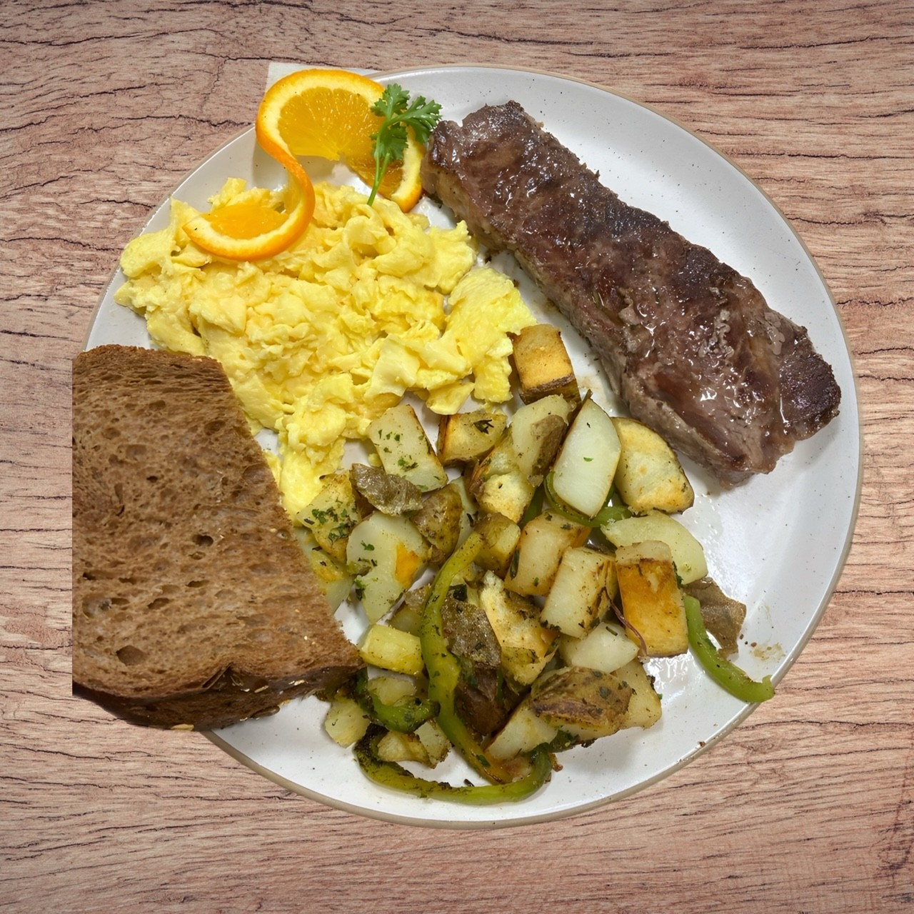 A white plate topped with scrambled eggs steak potatoes and toast