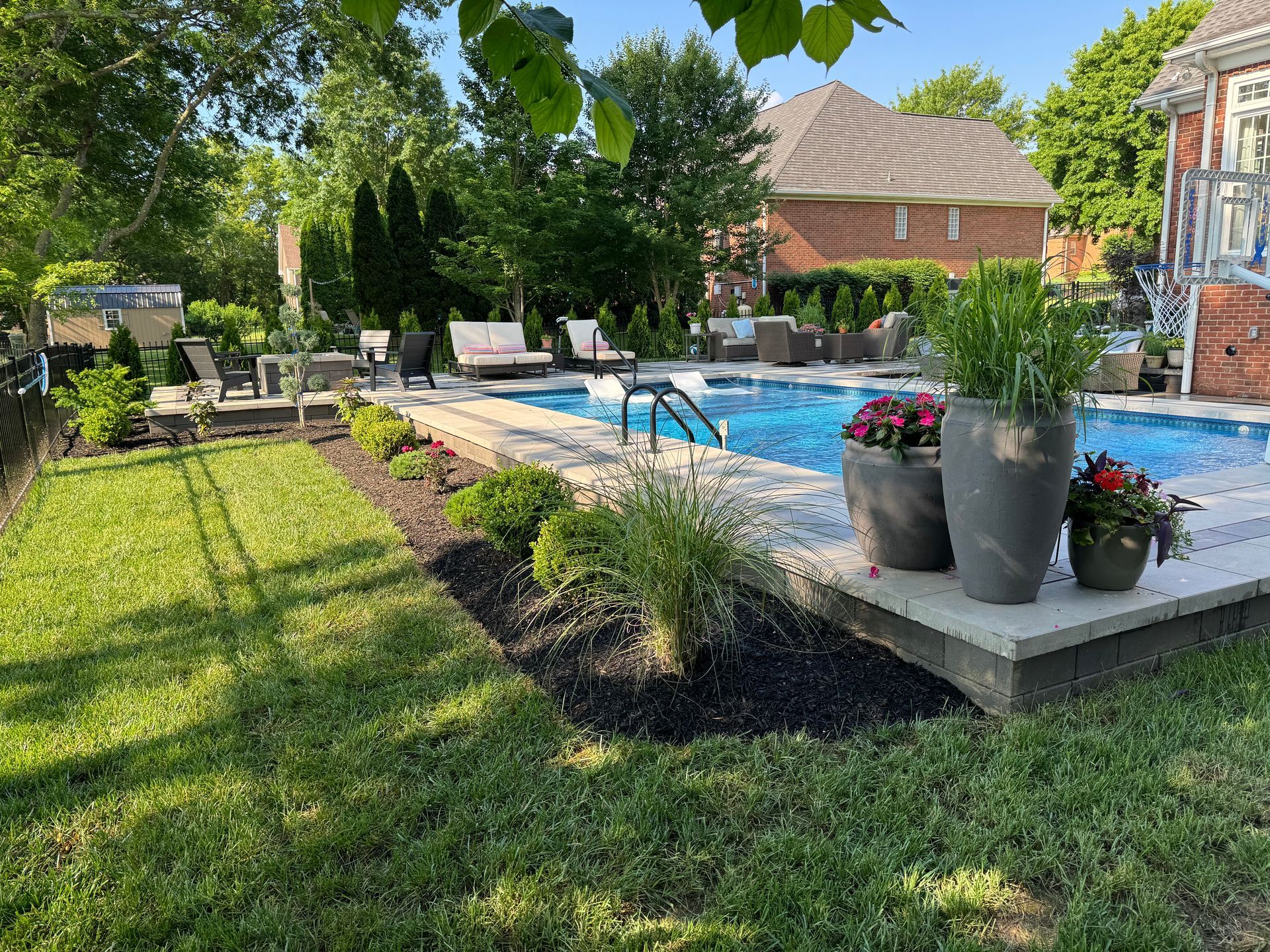 There is a large swimming pool in the backyard of a house.