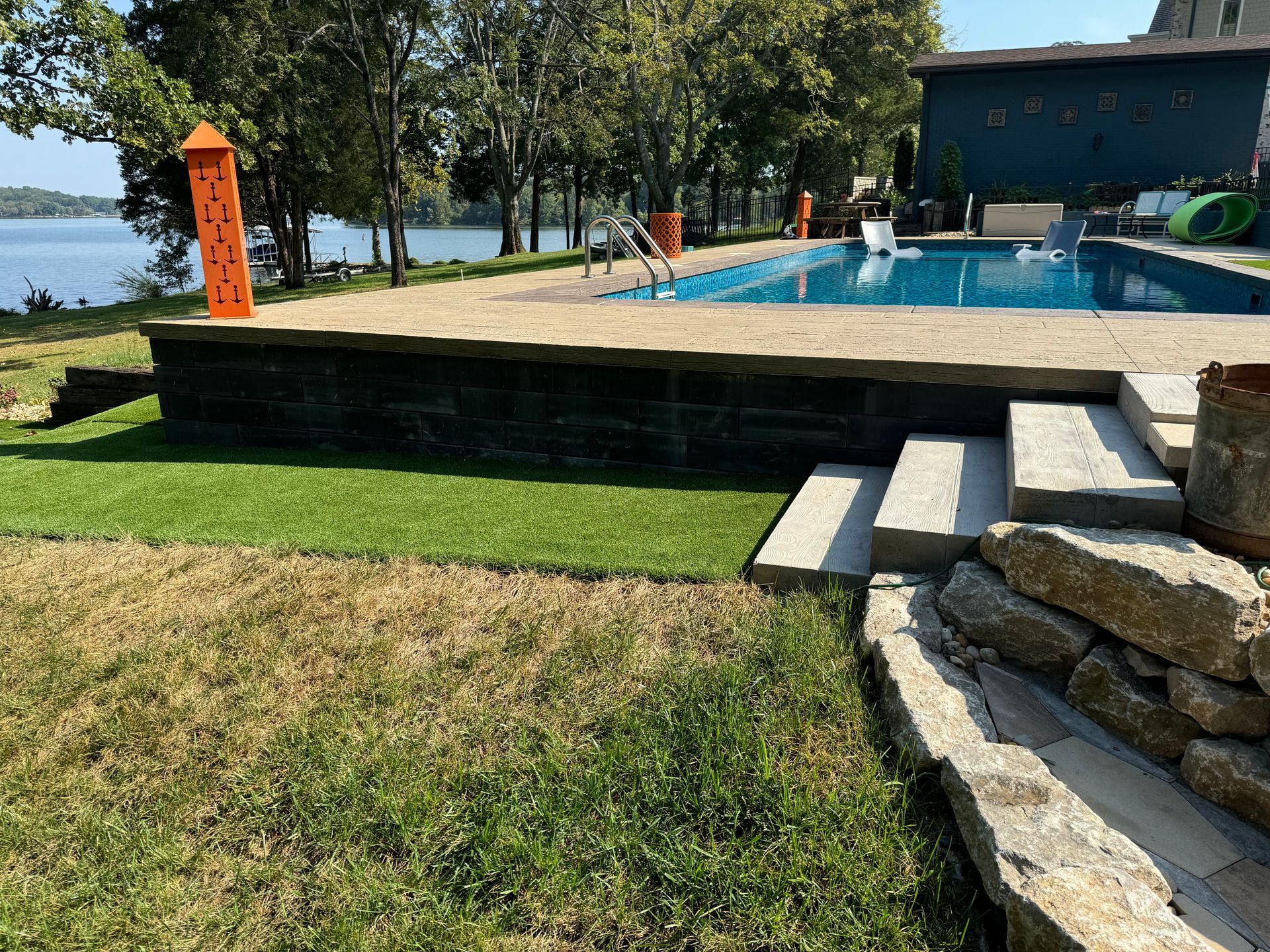 A large swimming pool is surrounded by a lush green lawn.