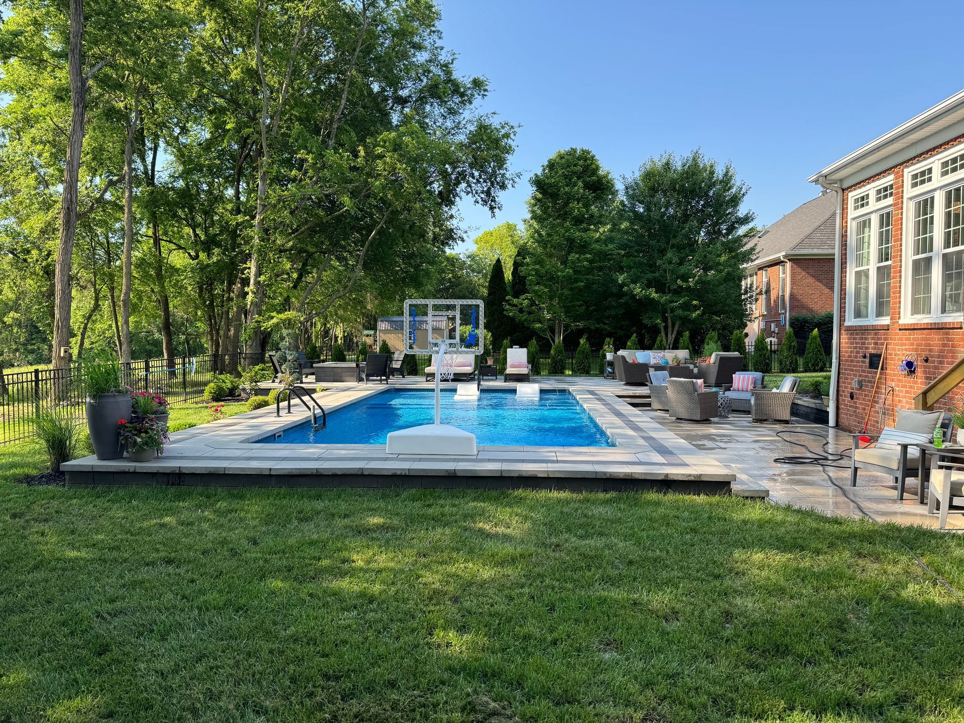 There is a large swimming pool in the backyard of a house.