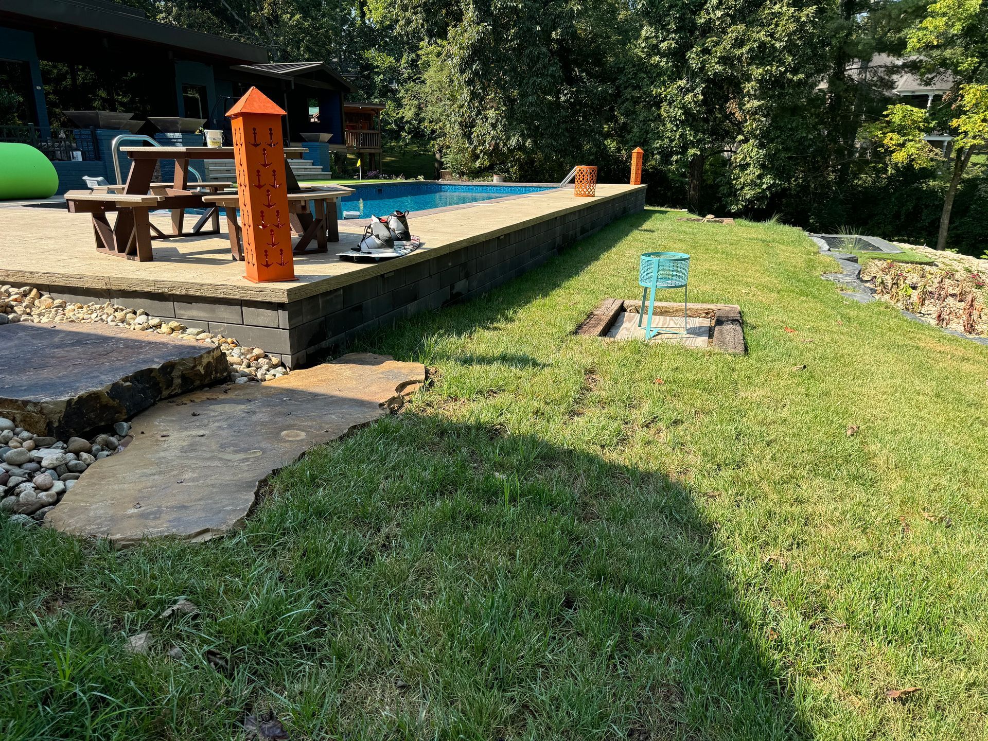 There is a swimming pool in the backyard with a picnic table and chairs.