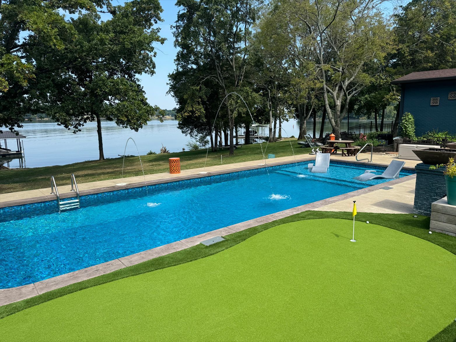A large swimming pool with a putting green in front of it