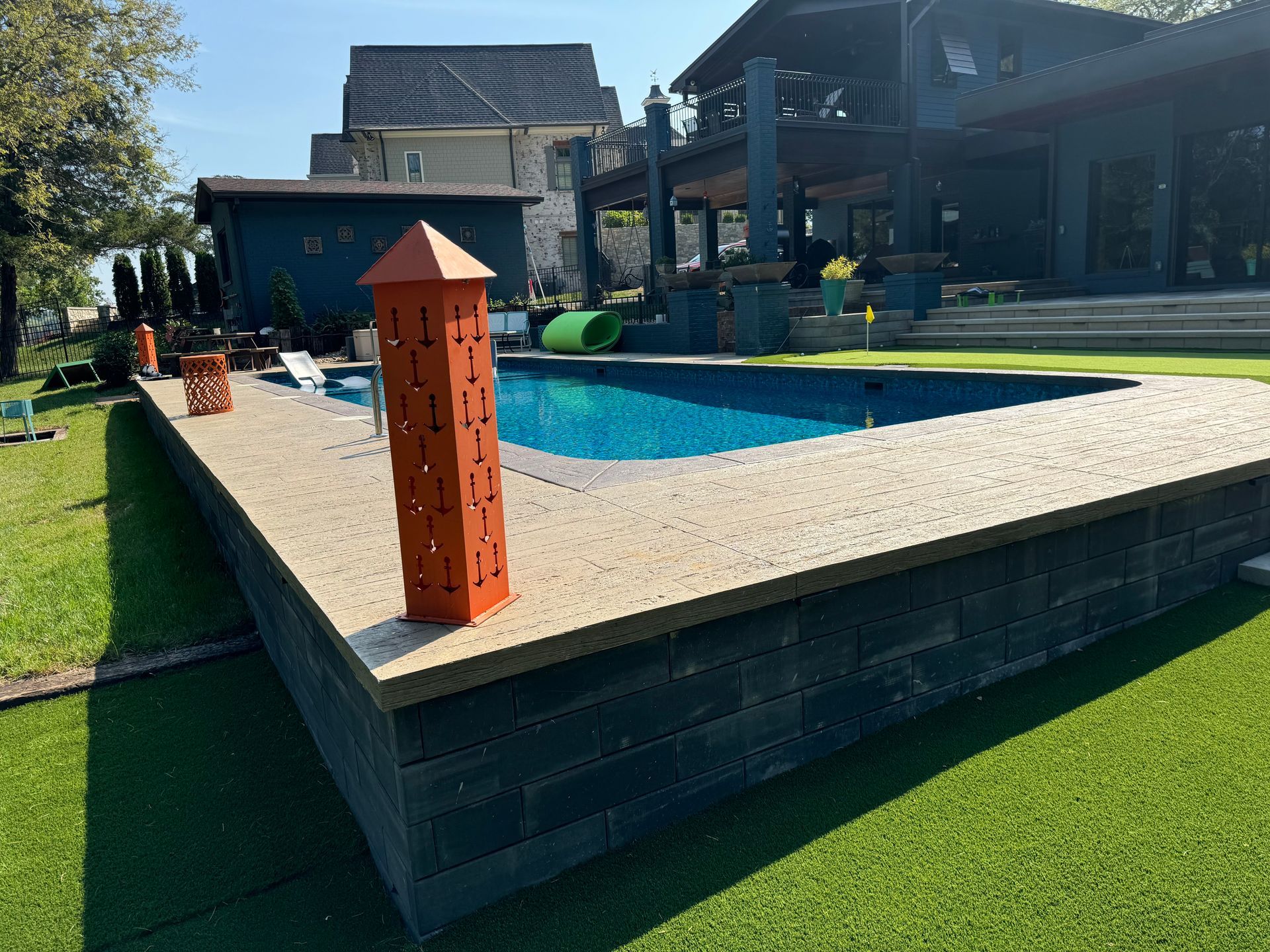 There is a large swimming pool in the backyard of a house.