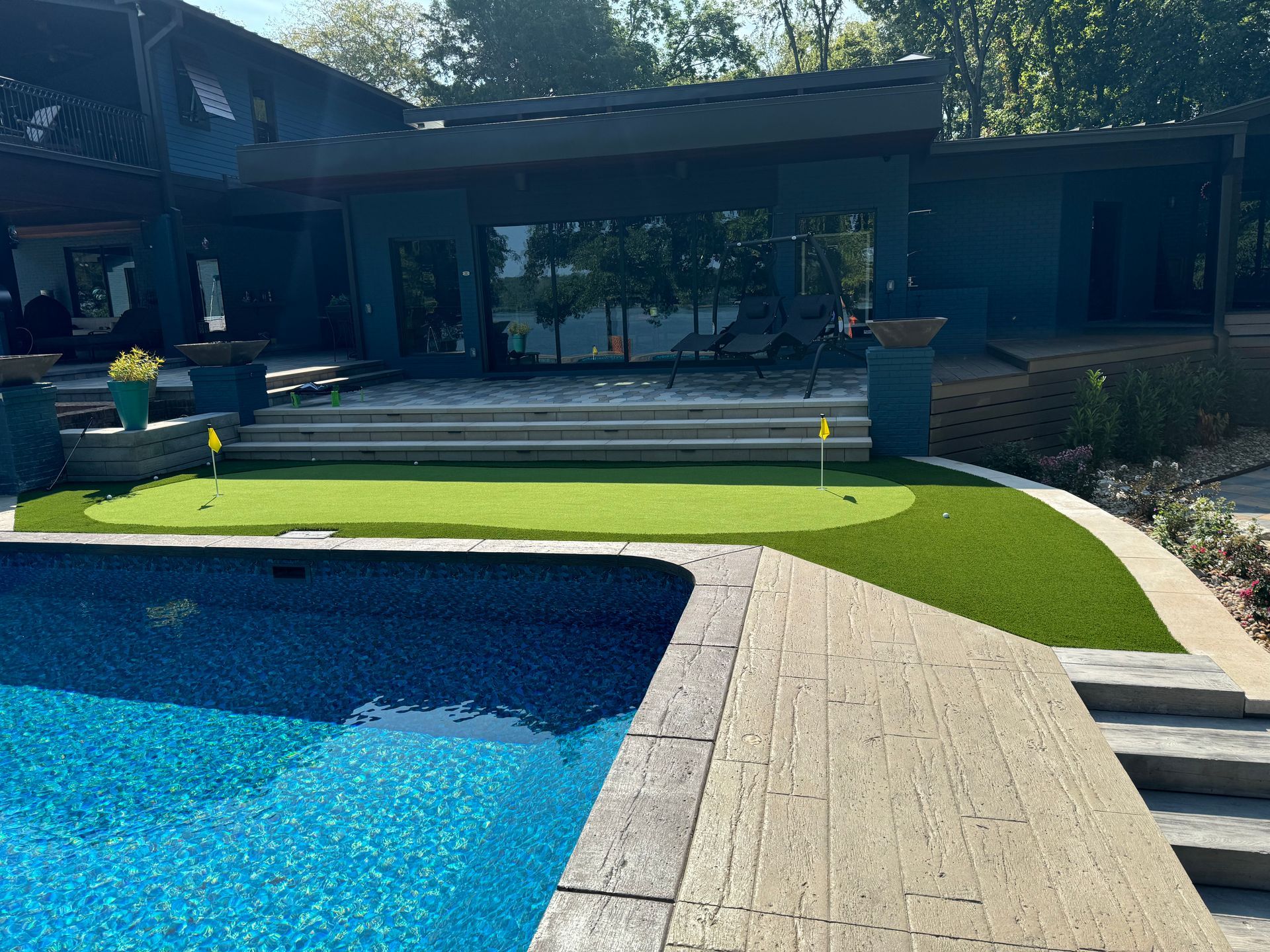 A swimming pool with a putting green in front of a house.