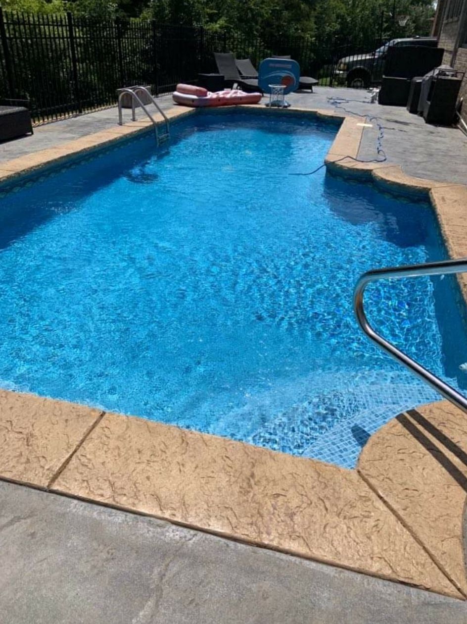 A large swimming pool filled with blue water in a backyard.