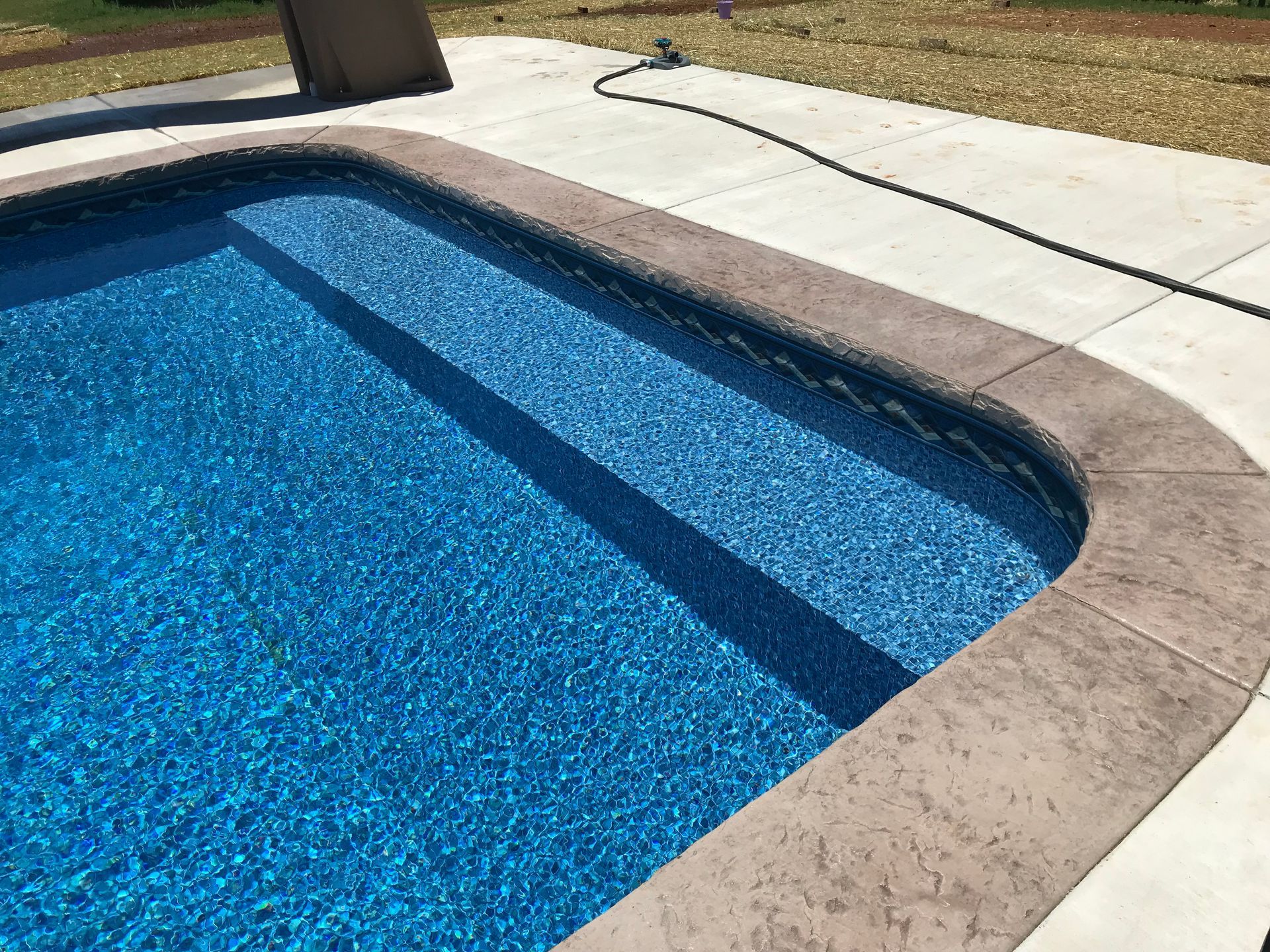 A swimming pool with a hose attached to the edge of it.