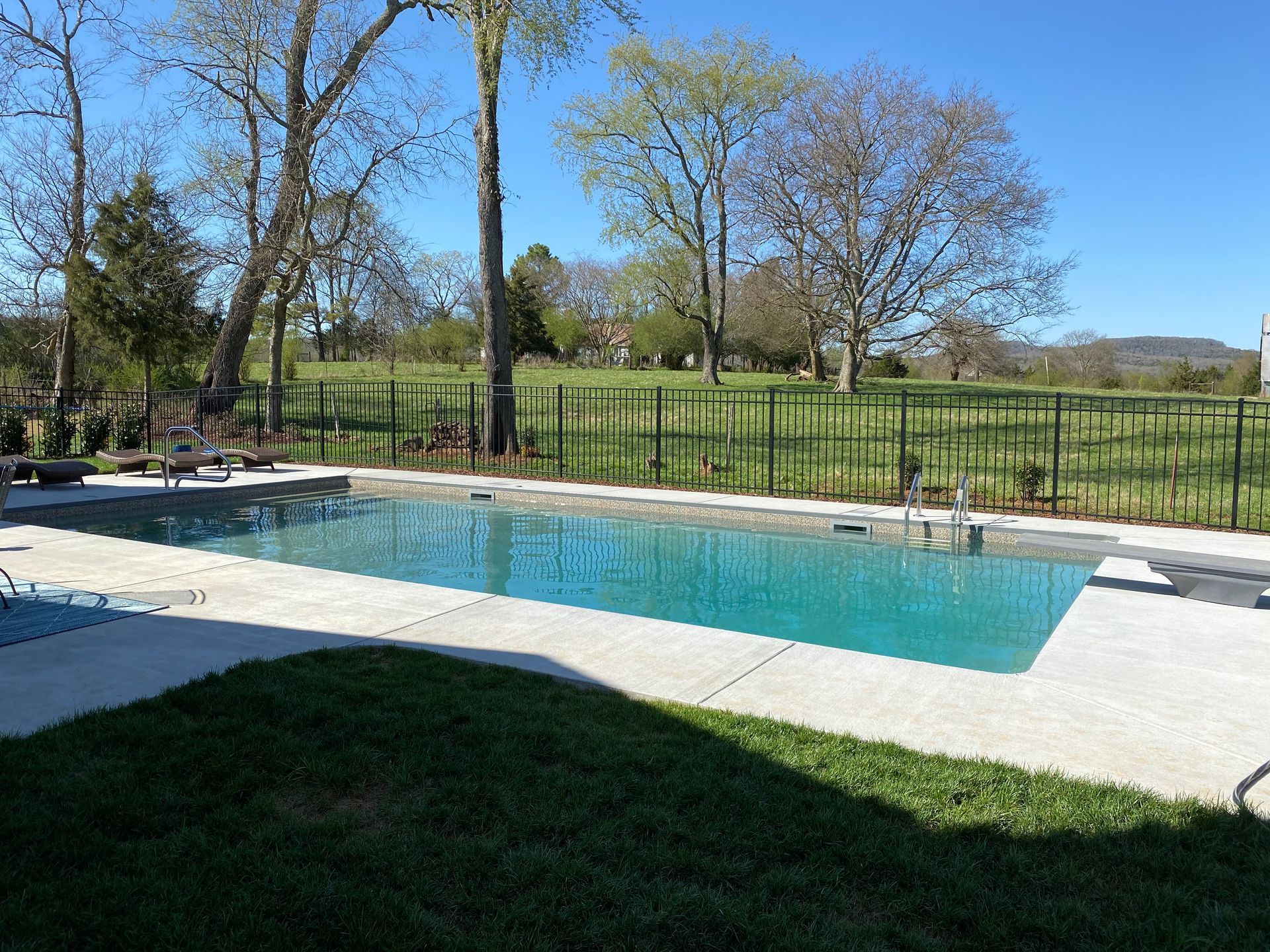 A large swimming pool surrounded by grass and trees