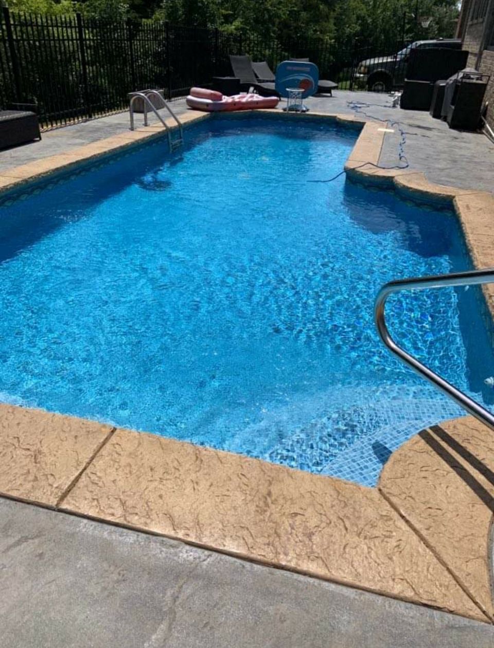 A large swimming pool filled with blue water in a backyard.