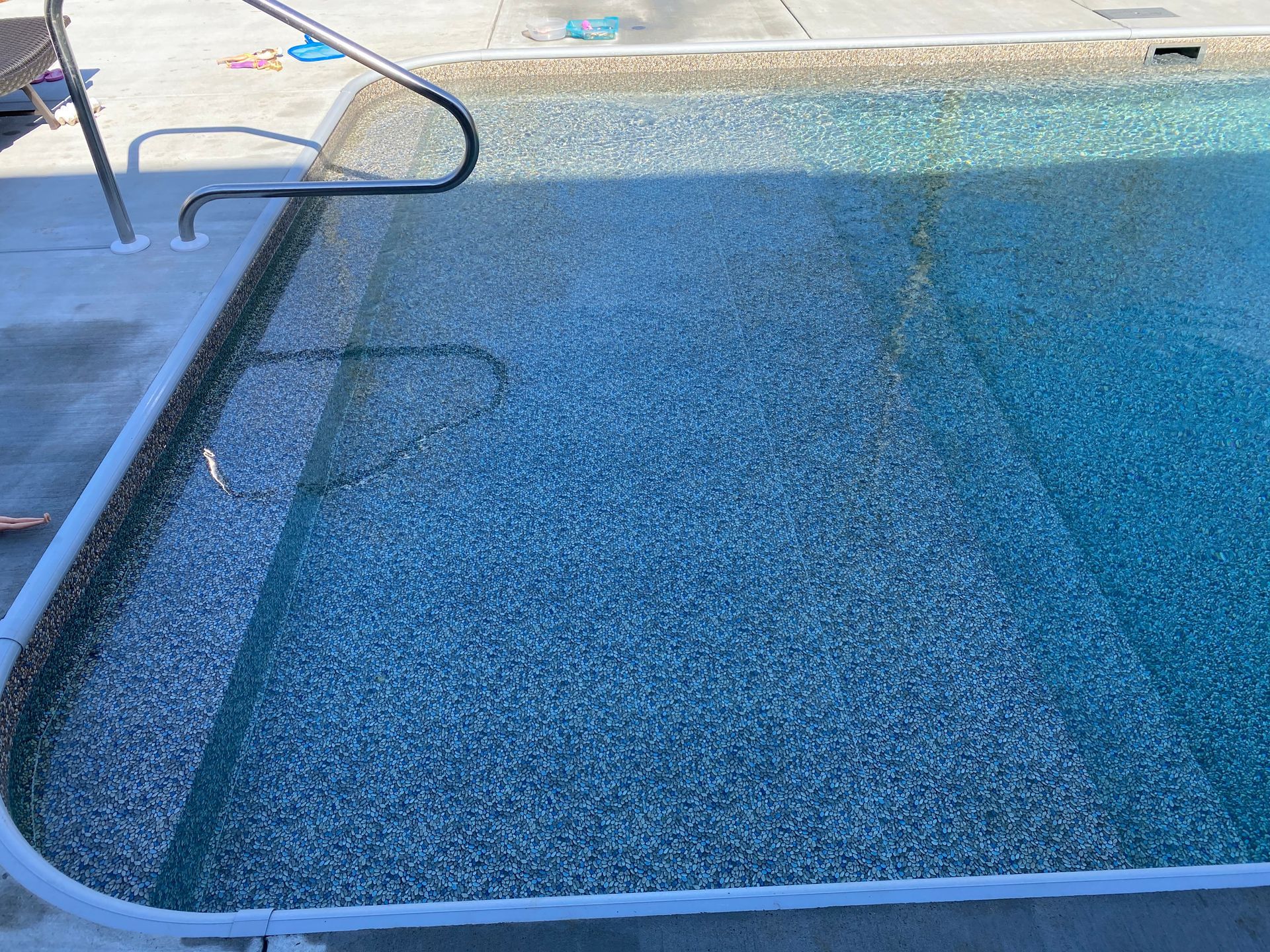 A swimming pool with a hand rail and steps leading into it.