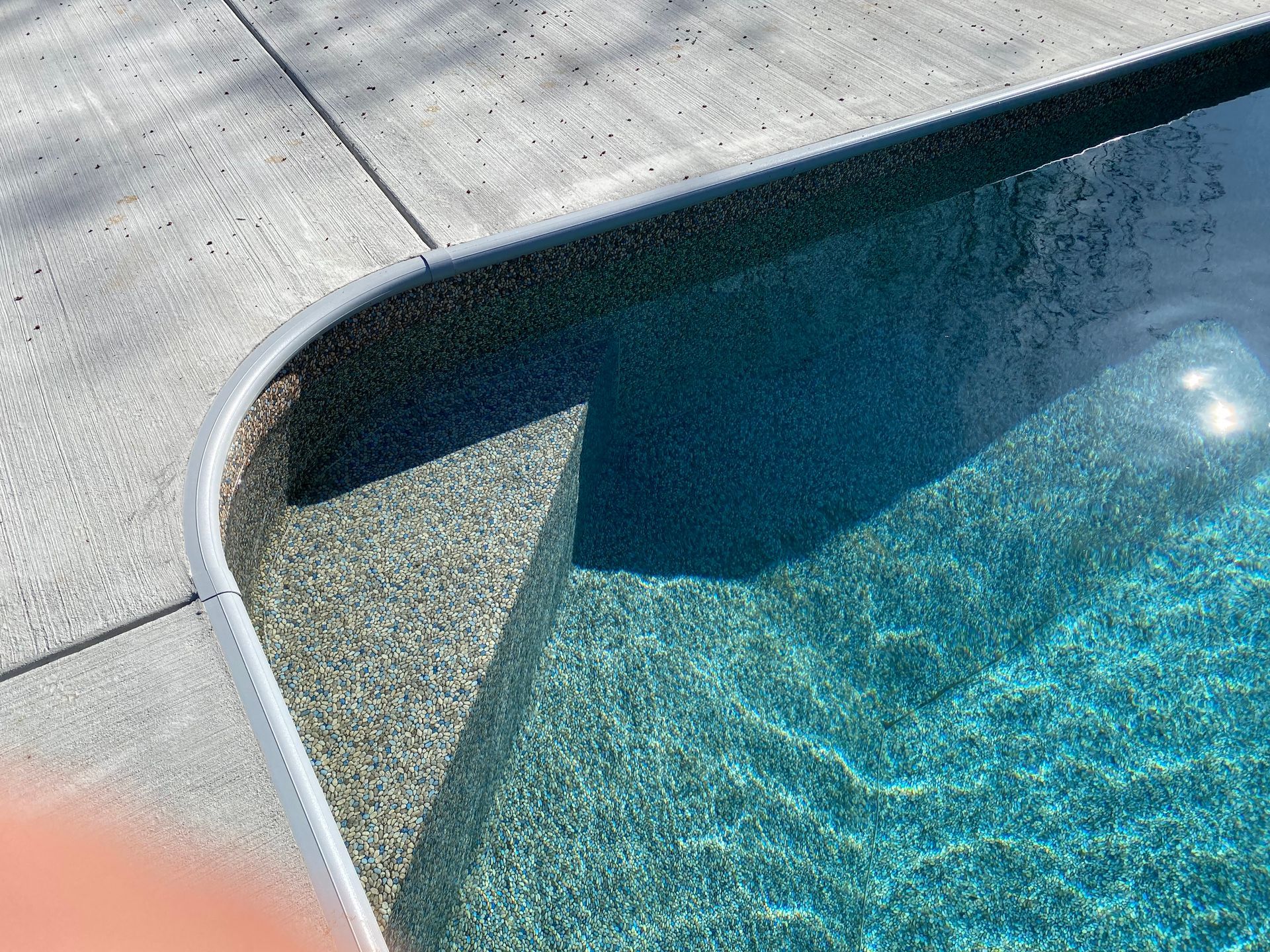 A person is standing next to a swimming pool.