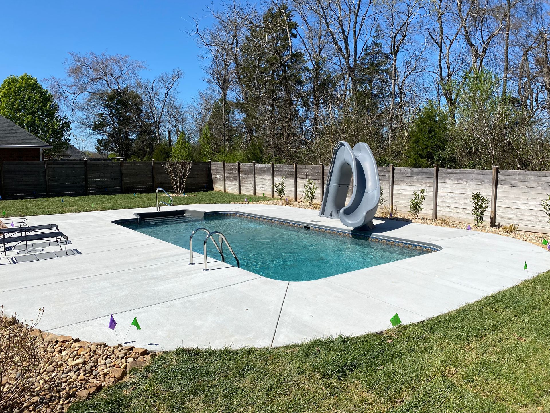 A large swimming pool is in the backyard of a house.
