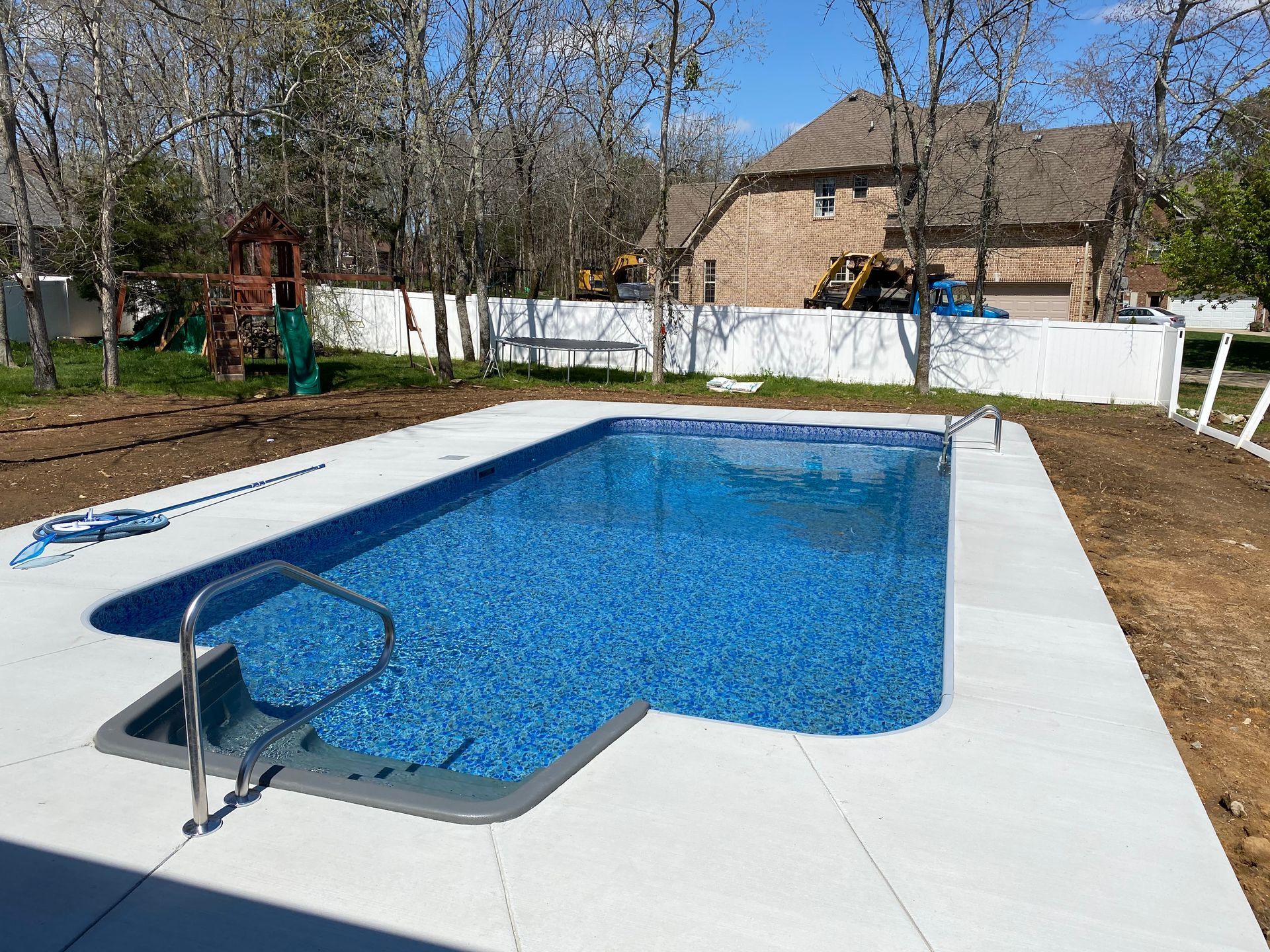 A large swimming pool is in the backyard of a house.