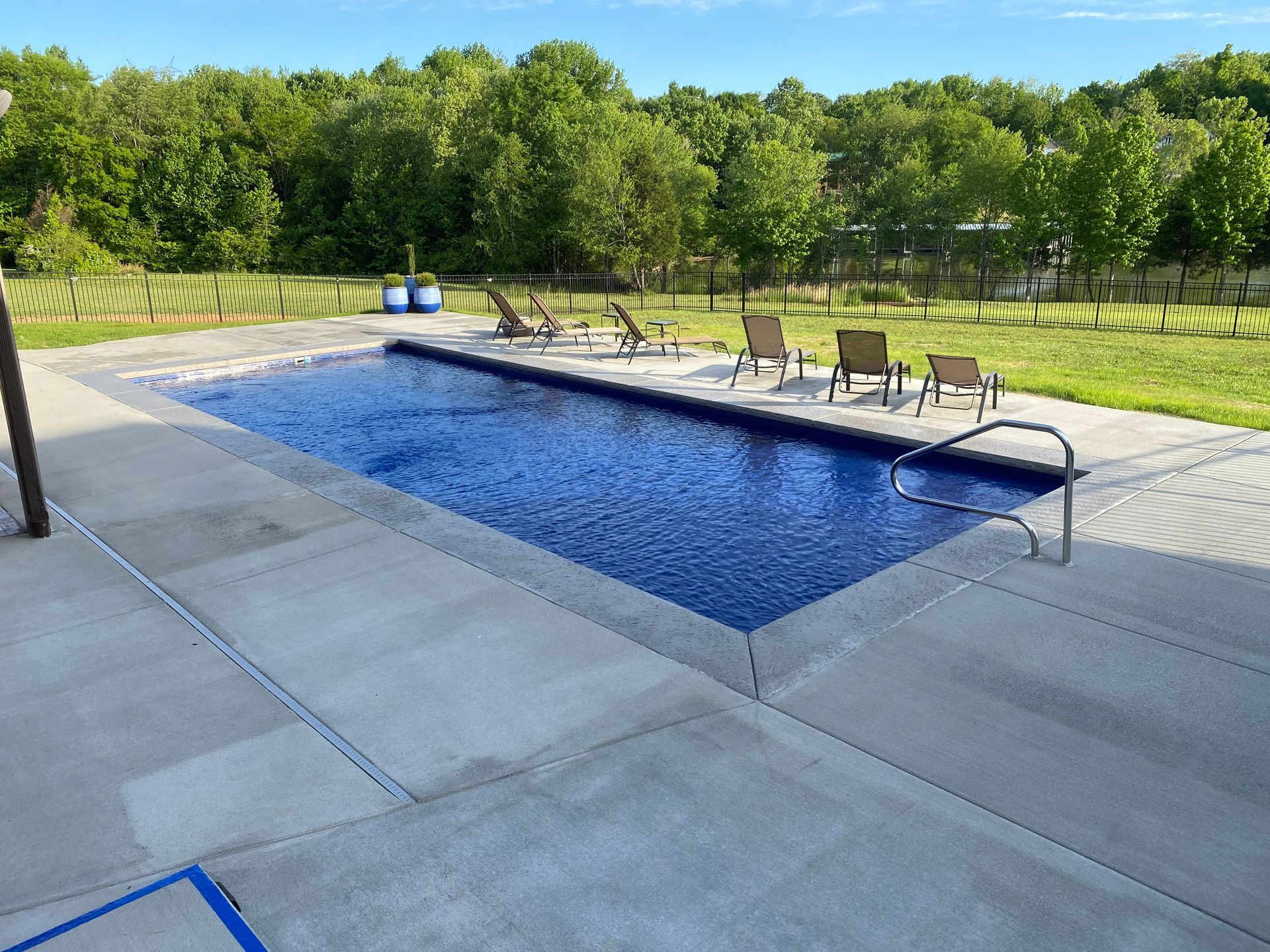 A large swimming pool surrounded by chairs and trees