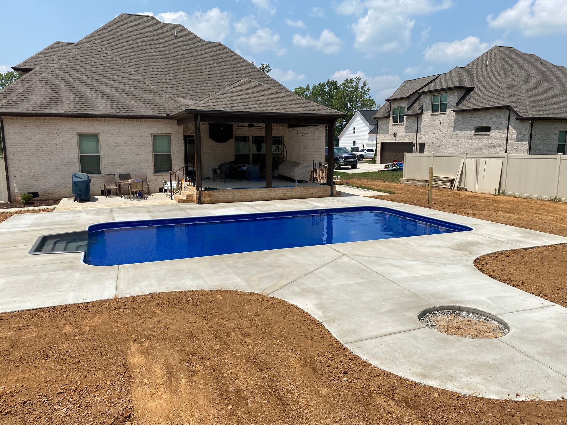 A large swimming pool is in the backyard of a house.