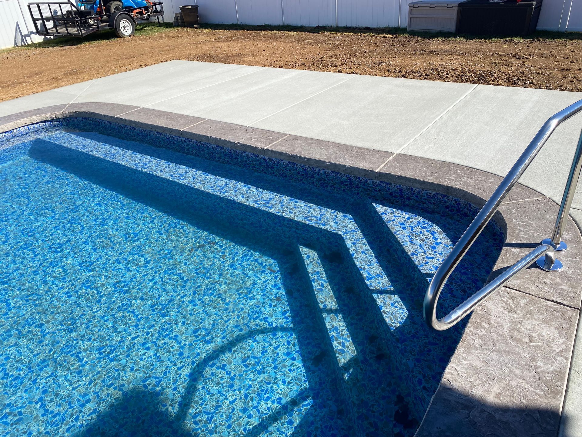 A swimming pool with blue tiles and a metal railing
