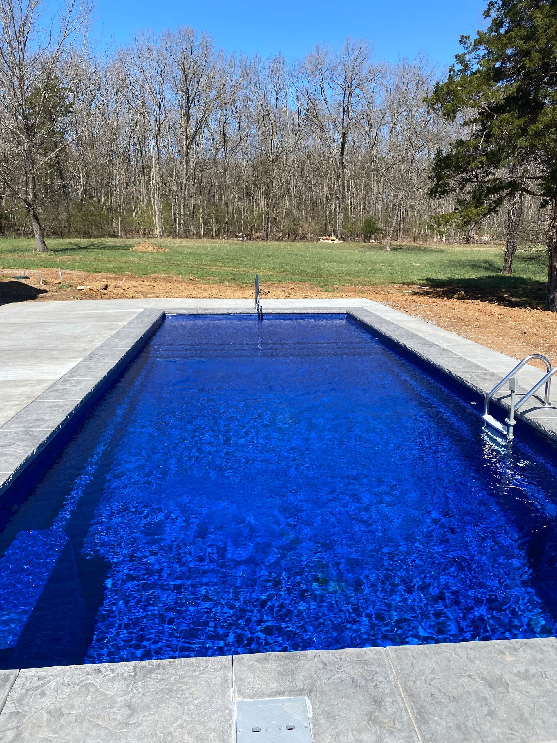 A large blue swimming pool with trees in the background