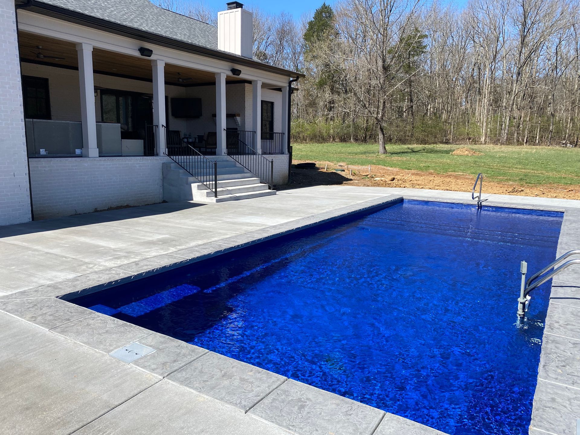 A large blue swimming pool is in front of a house.