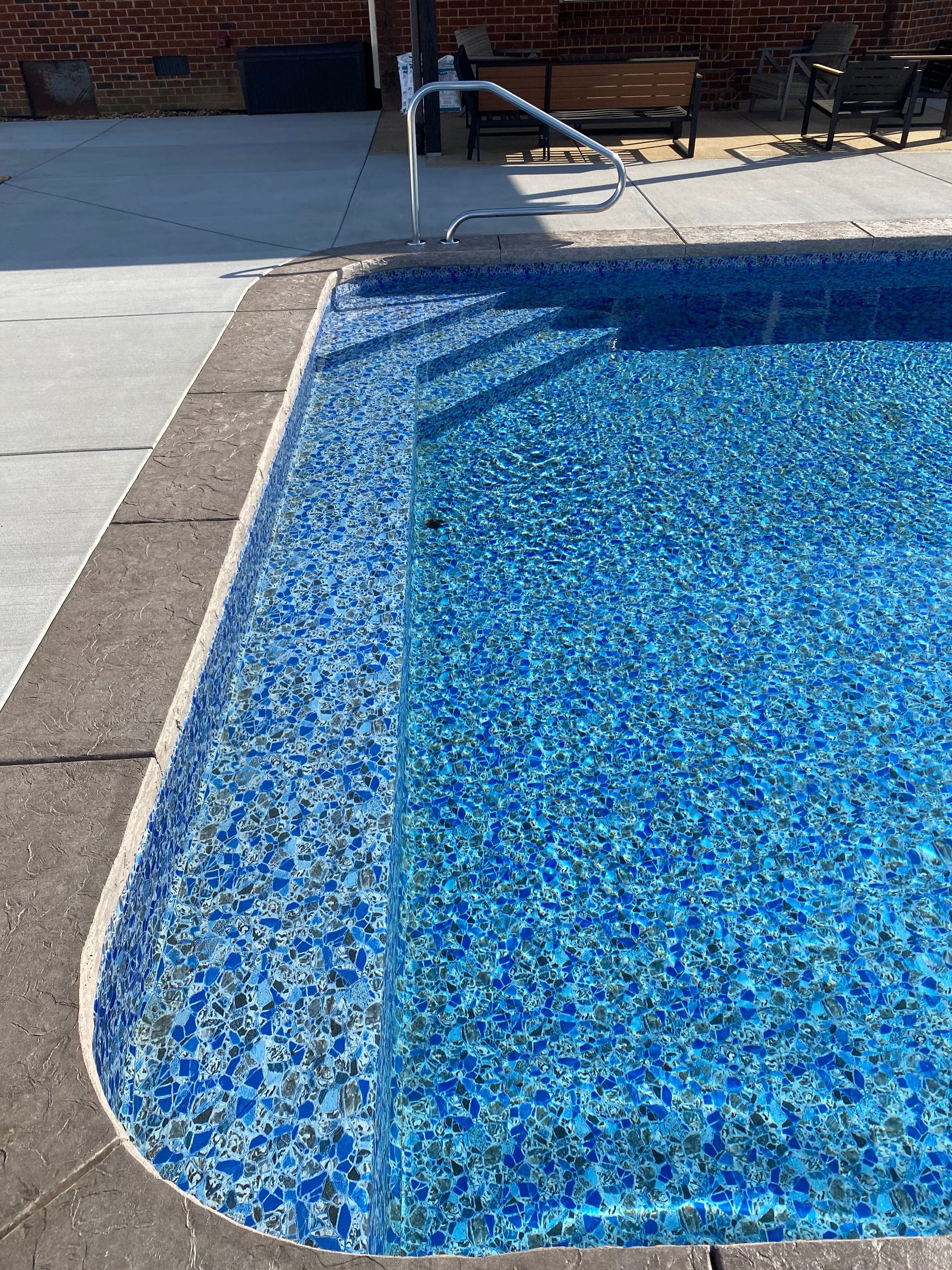 A swimming pool with blue tiles and a white railing.