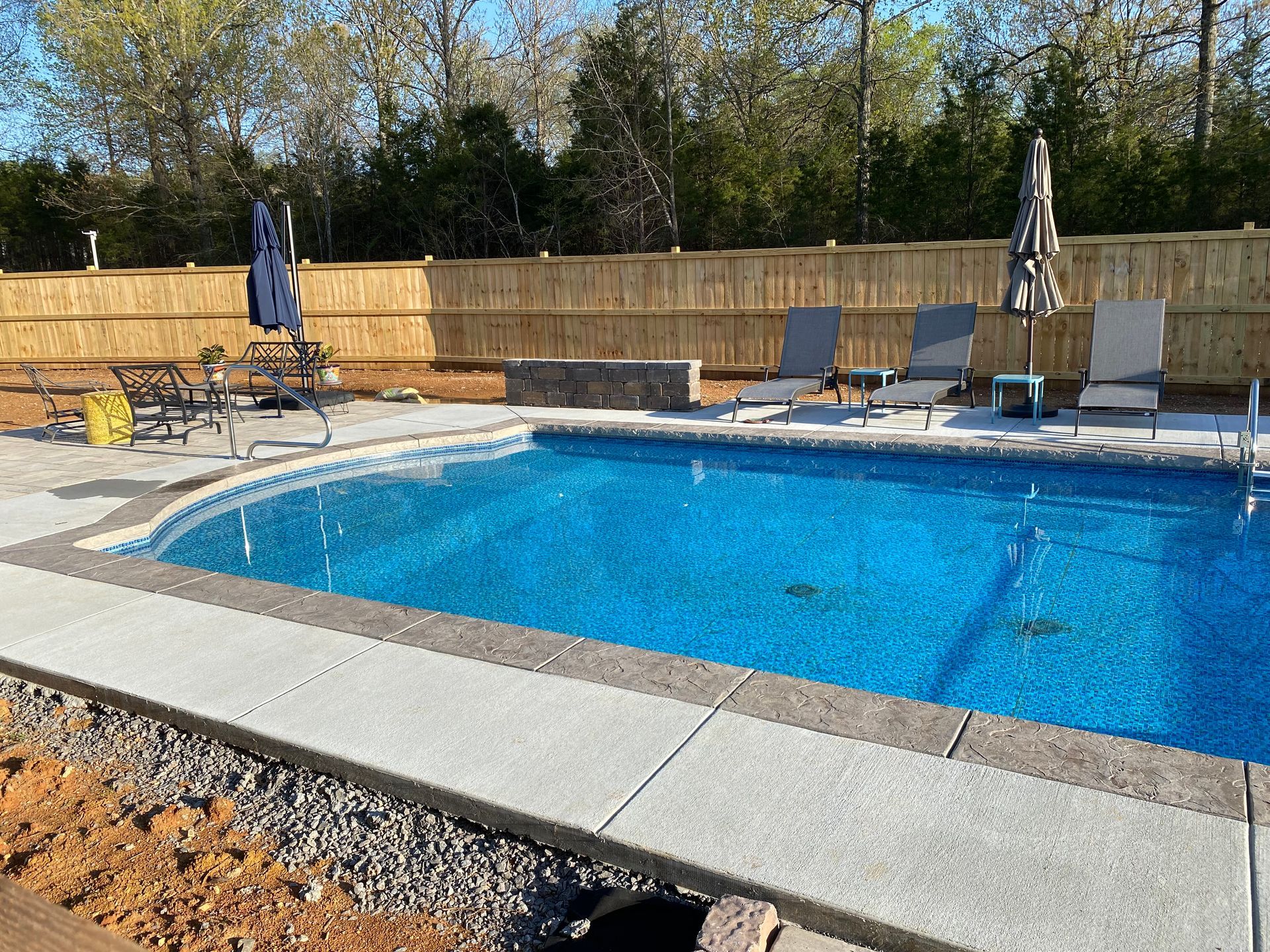 A large swimming pool is surrounded by chairs and umbrellas.