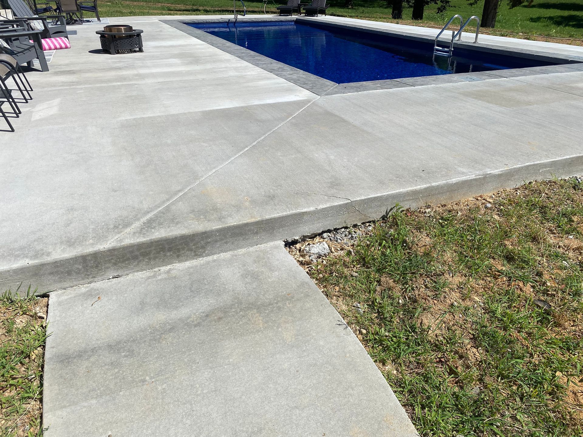 A concrete walkway leading to a large swimming pool.