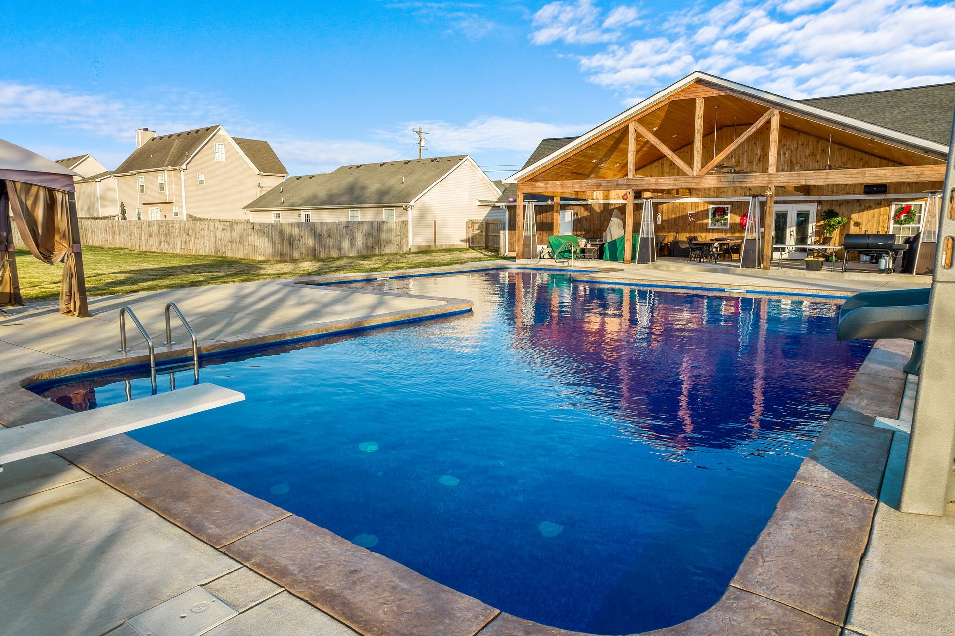 A large swimming pool is in the backyard of a house.