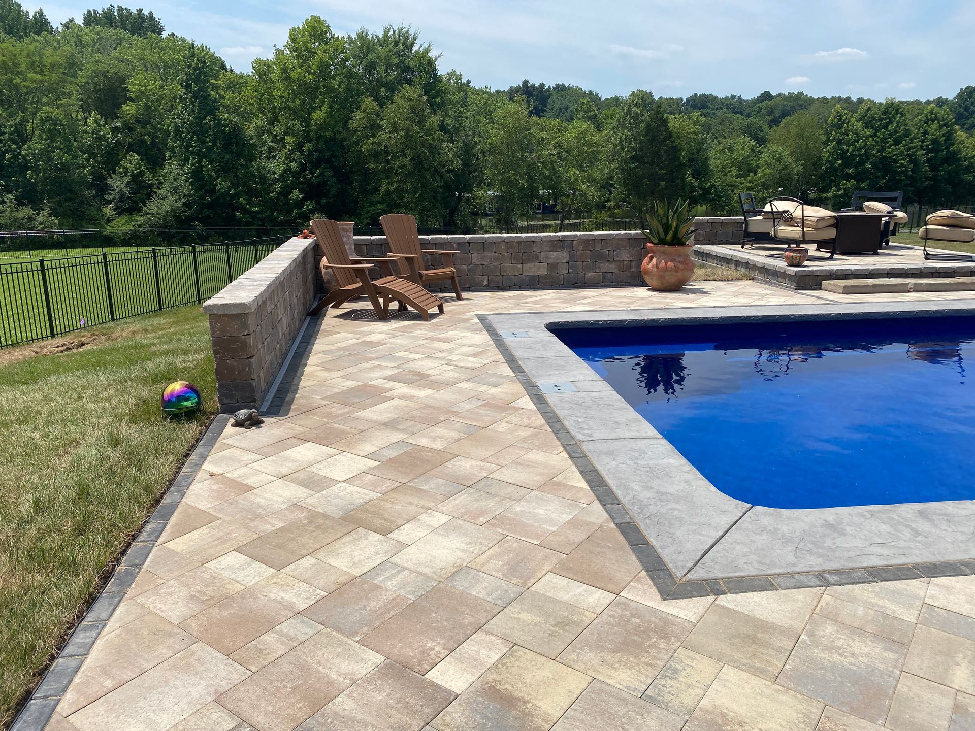A large swimming pool is surrounded by a patio and chairs.