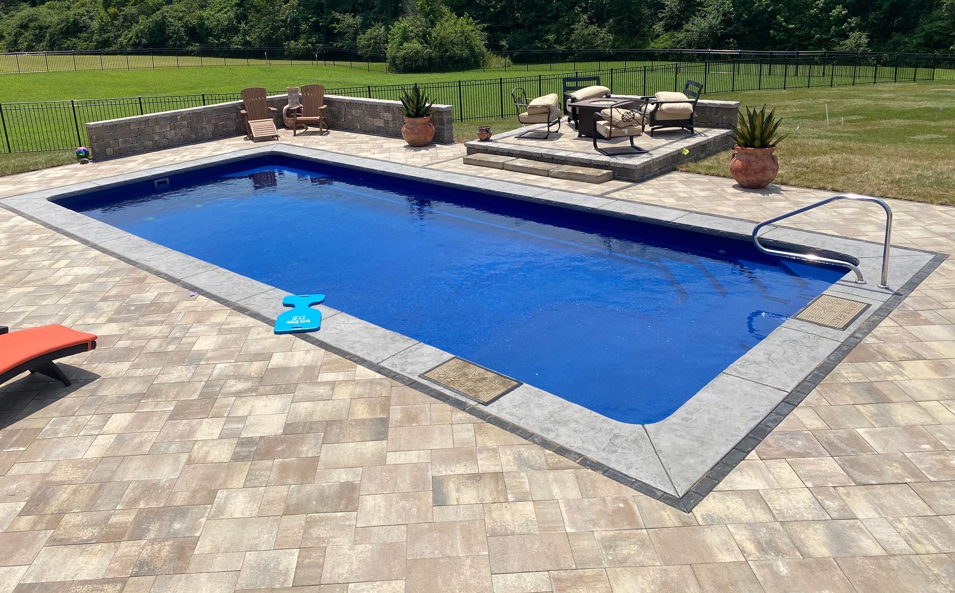 A large swimming pool is sitting on top of a brick patio.