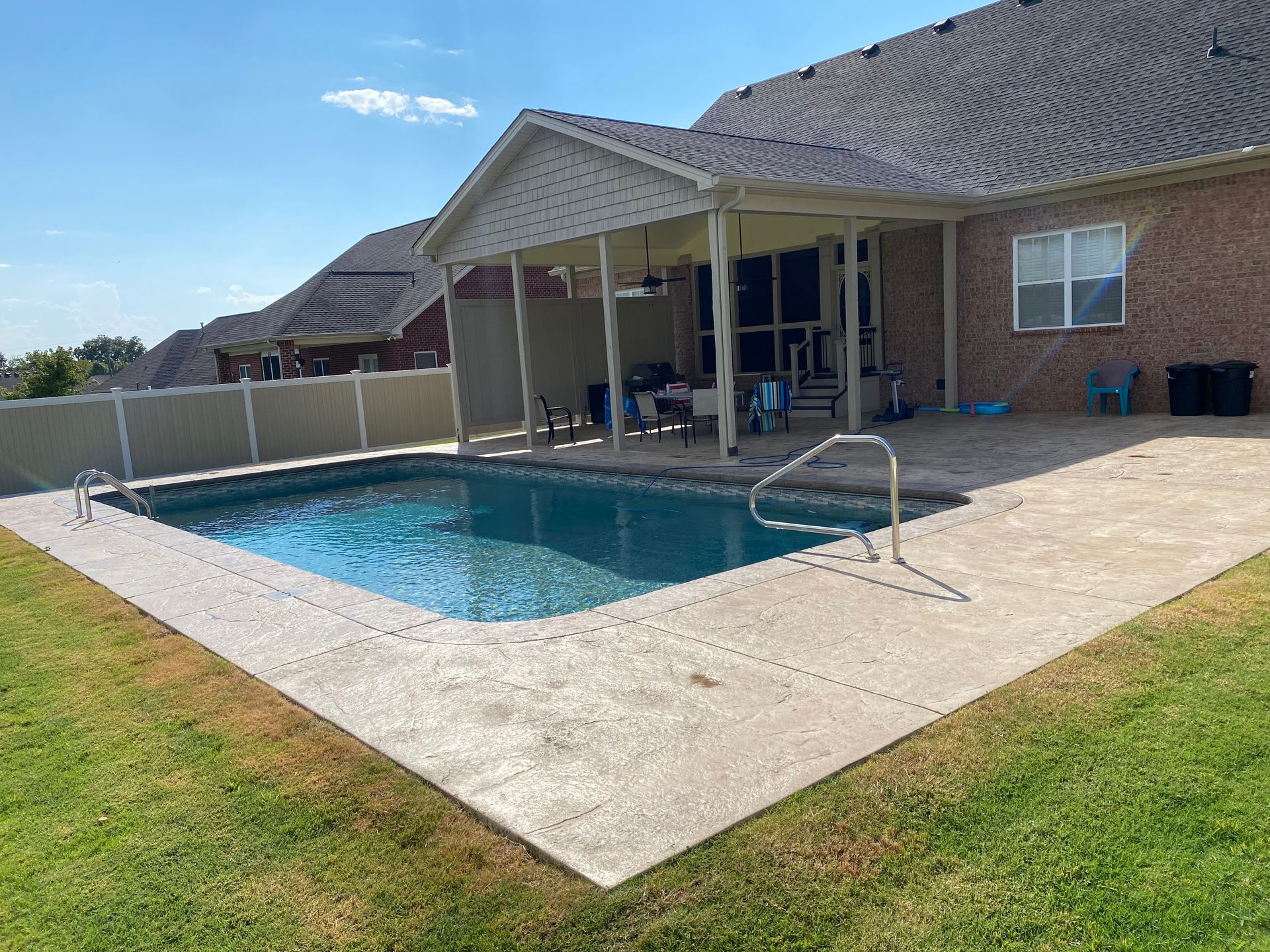 There is a large swimming pool in the backyard of a house.