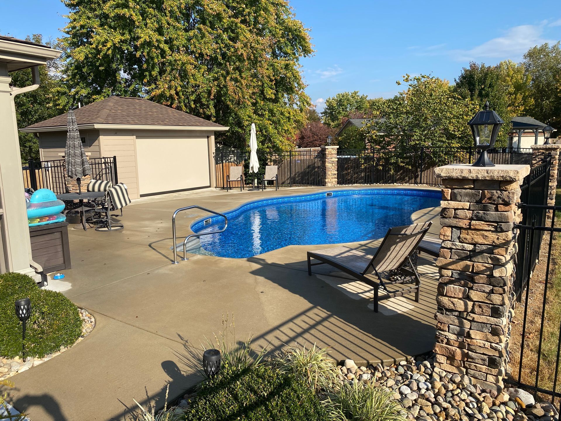 There is a large swimming pool in the backyard of a house.