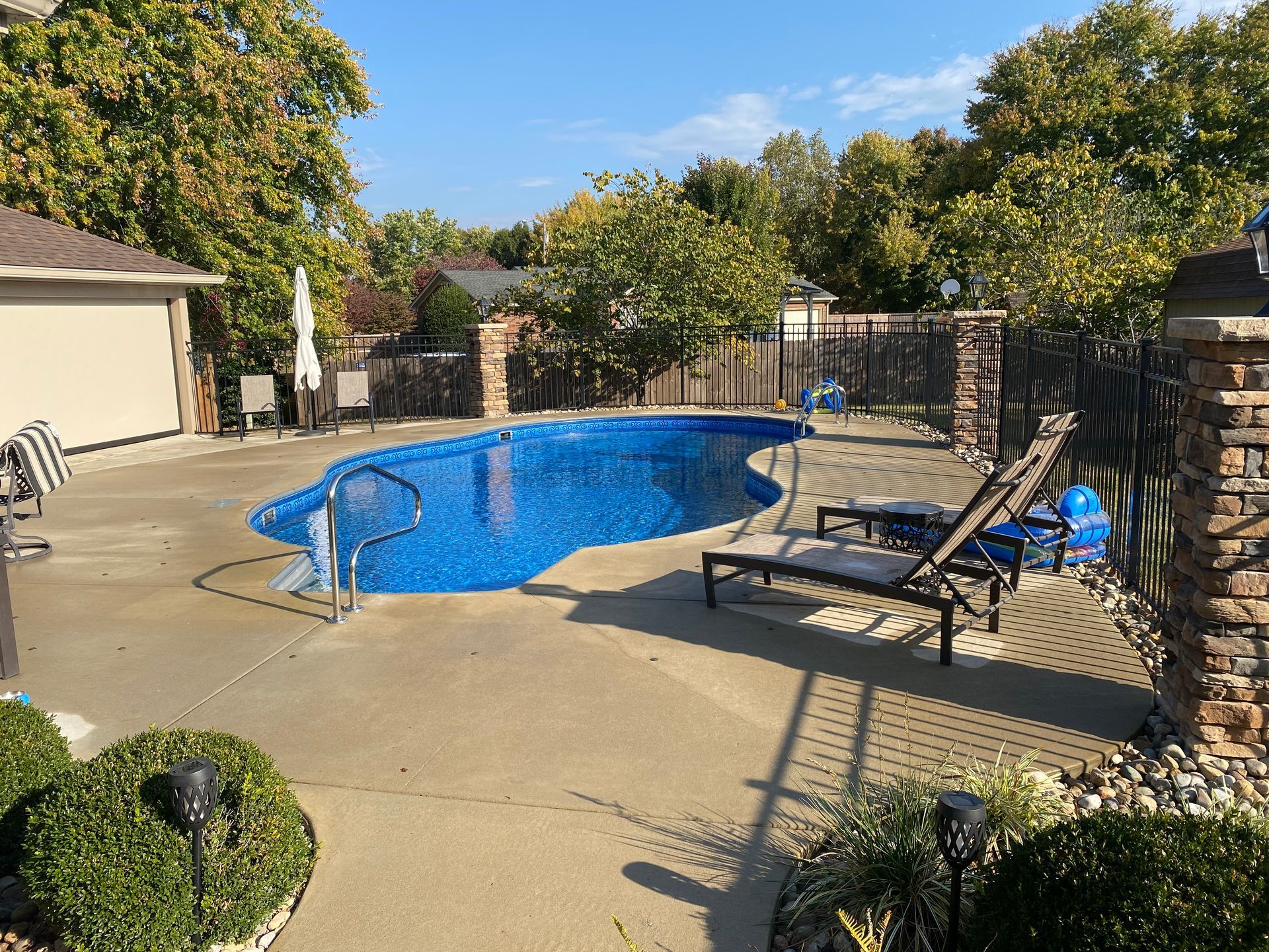 There is a large swimming pool in the backyard of a house.