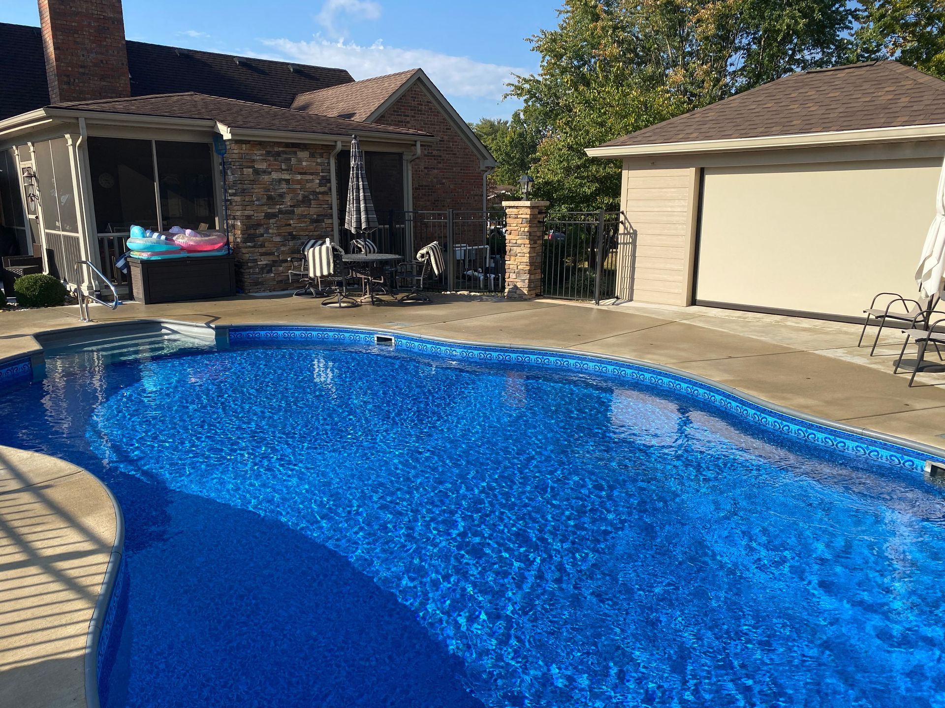 A large blue swimming pool is in the backyard of a house.