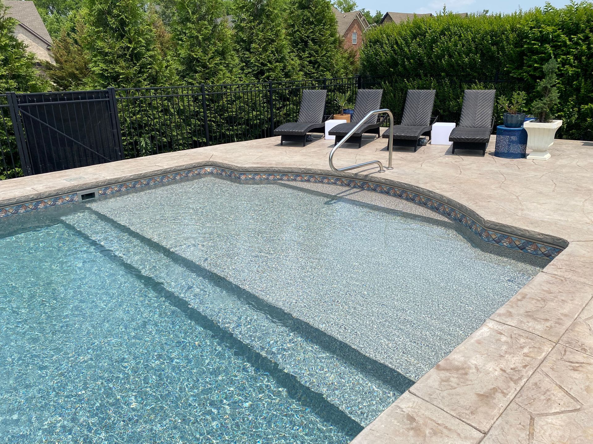 A large swimming pool with stairs and chairs around it.