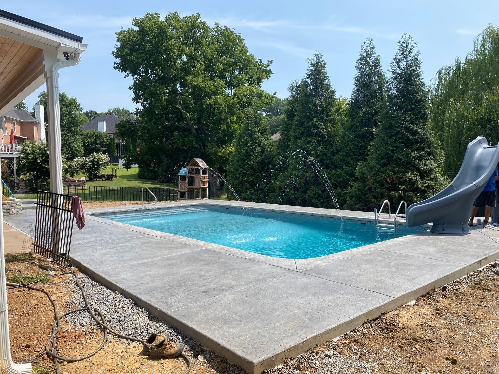 A large swimming pool with a slide in the backyard.