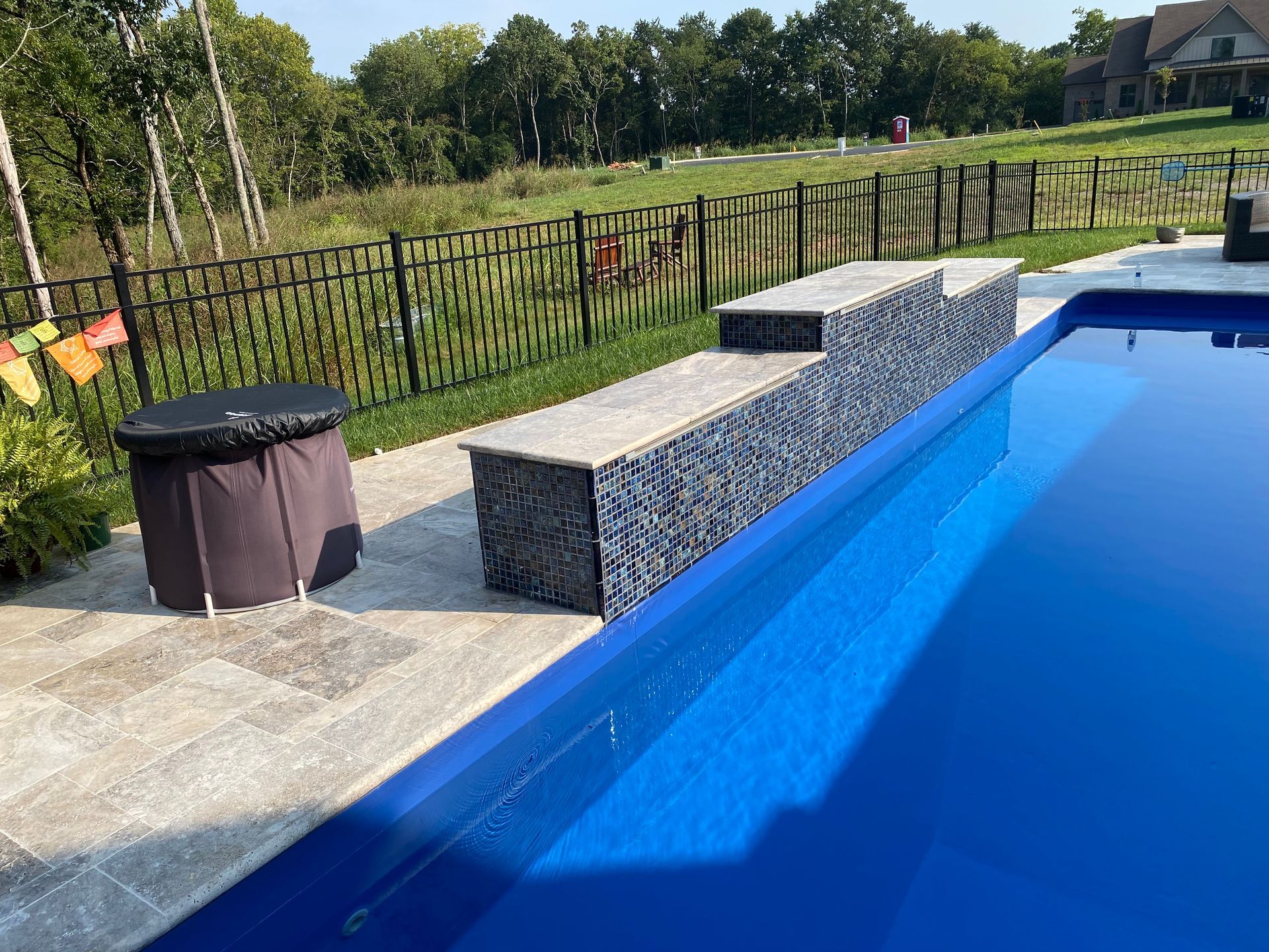 A large blue swimming pool with a fence surrounding it.