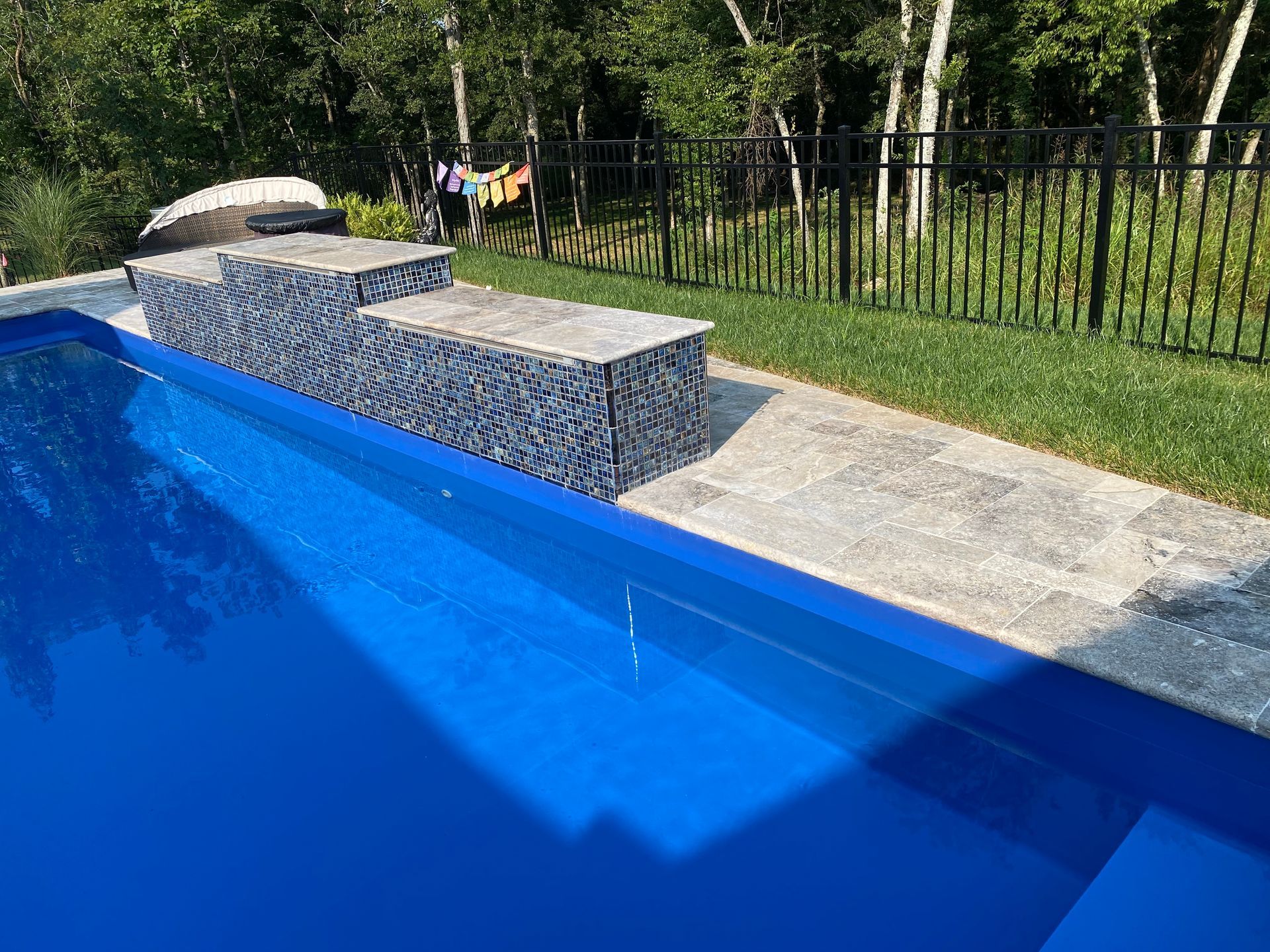 A large blue swimming pool with a black fence surrounding it.