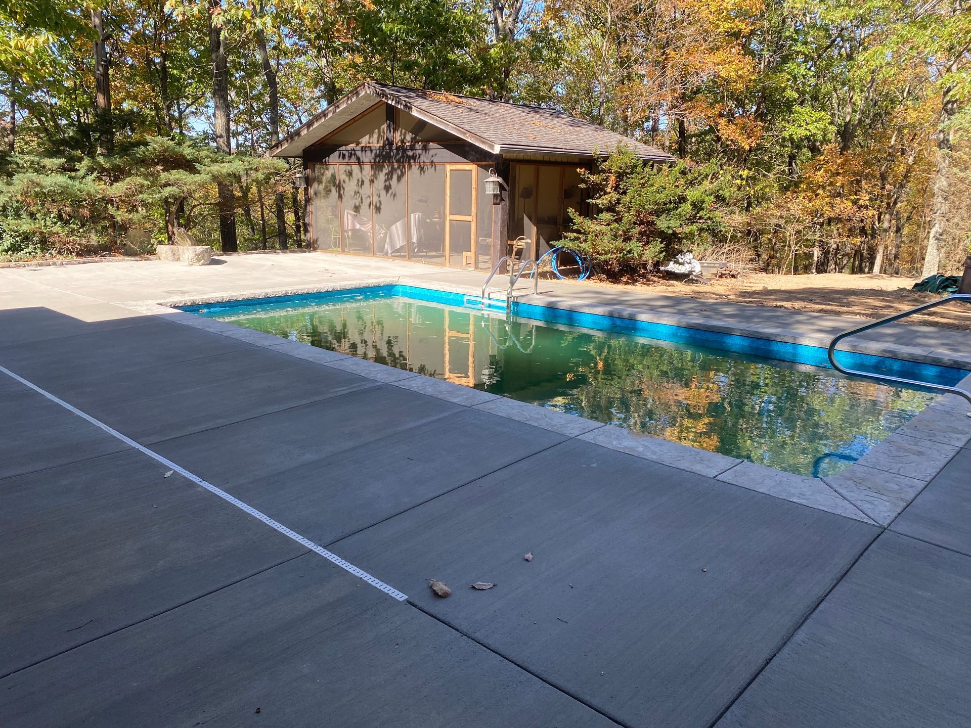 A large swimming pool with a house in the background