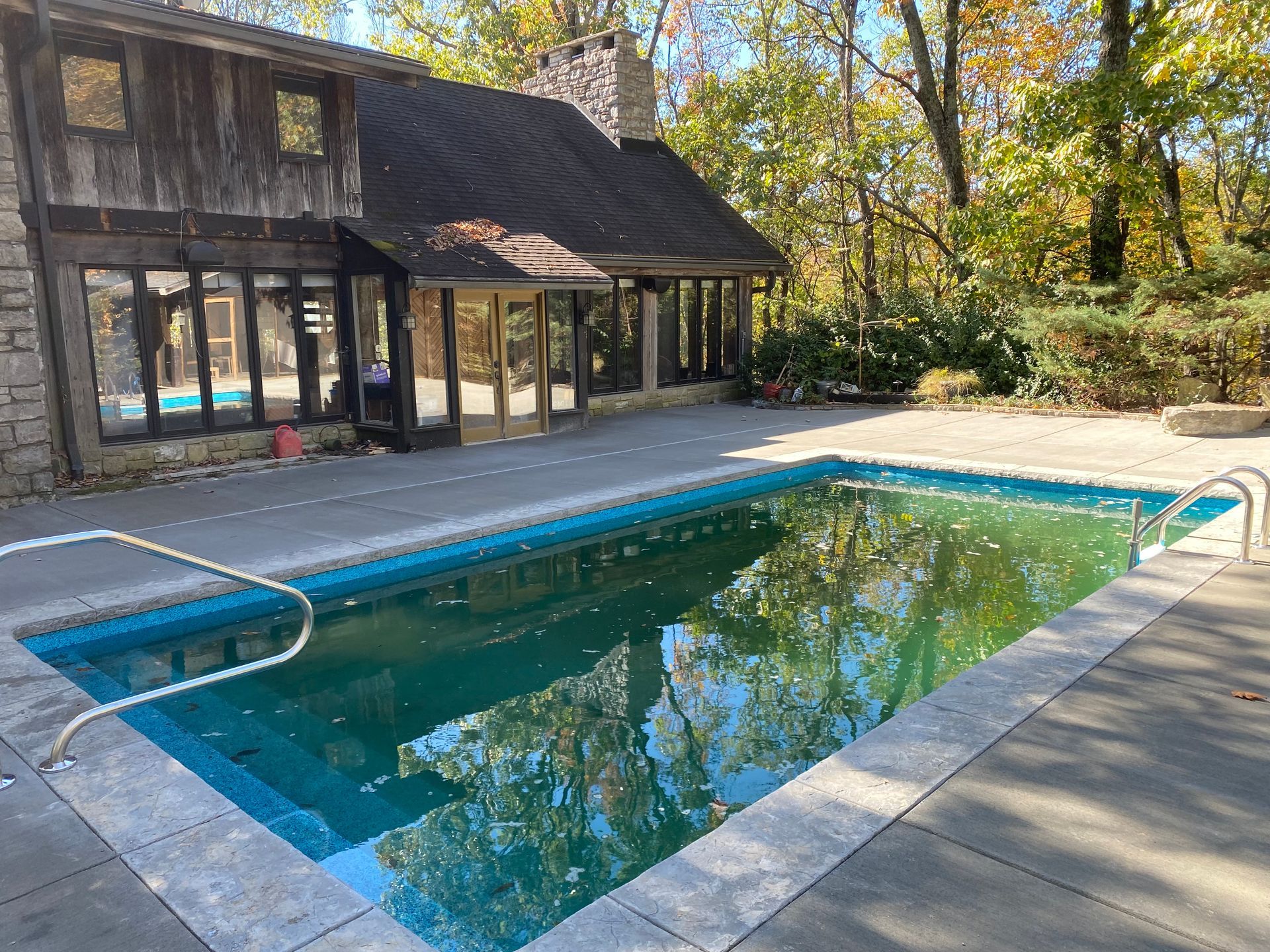 A large swimming pool with a house in the background