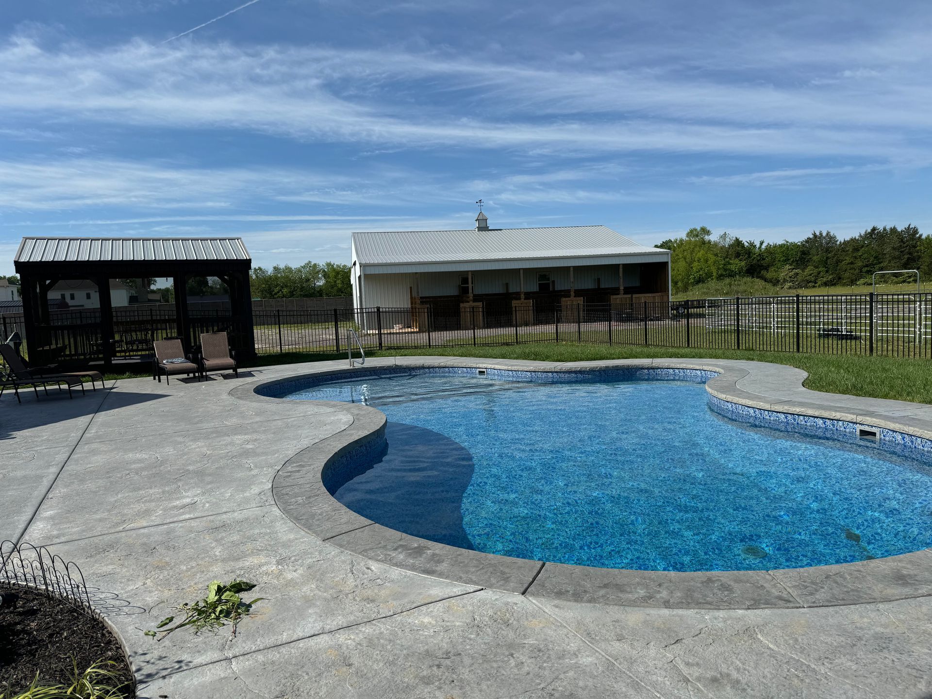 There is a large swimming pool in the backyard of a house.