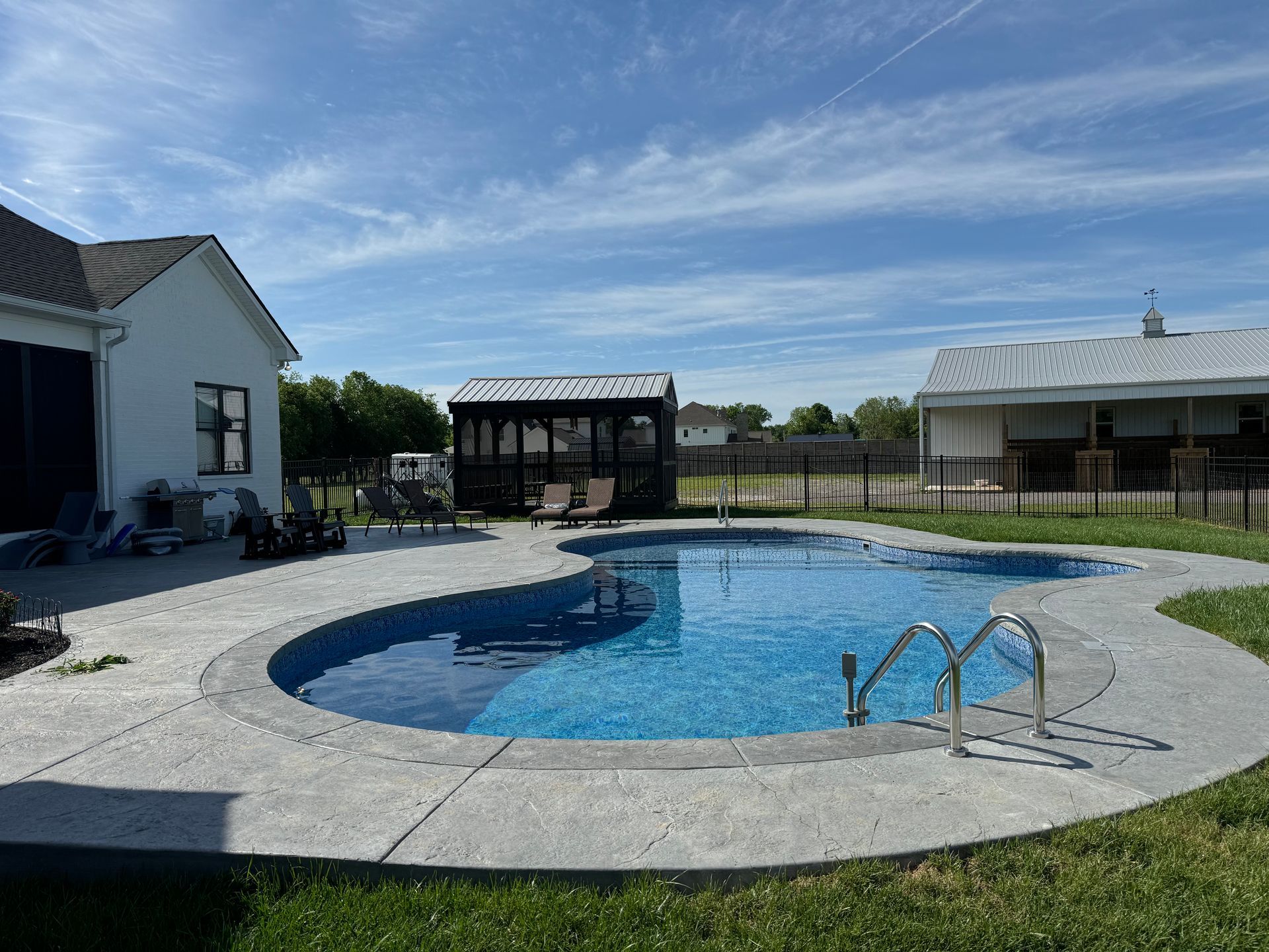 There is a large swimming pool in the backyard of a house.