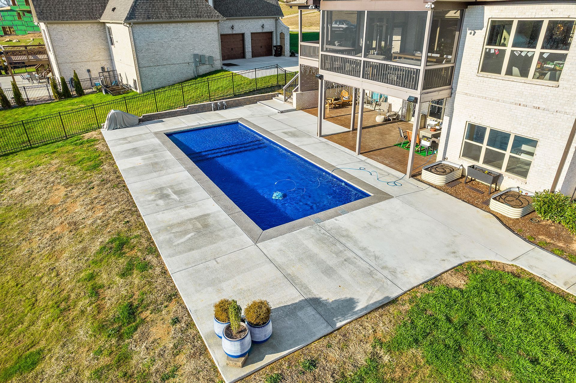 An aerial view of a large swimming pool in the backyard of a house.