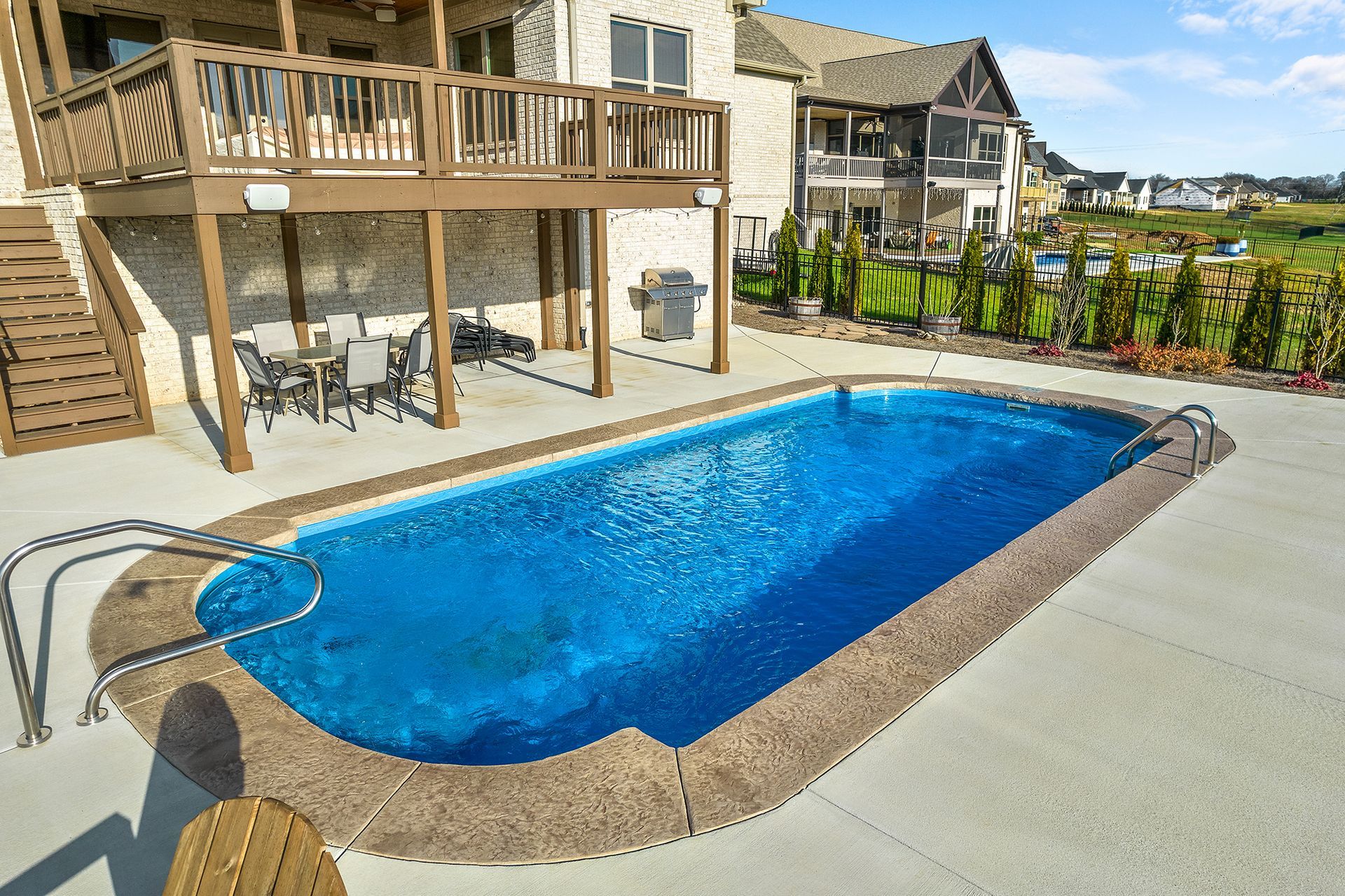 A large swimming pool in front of a house with a deck