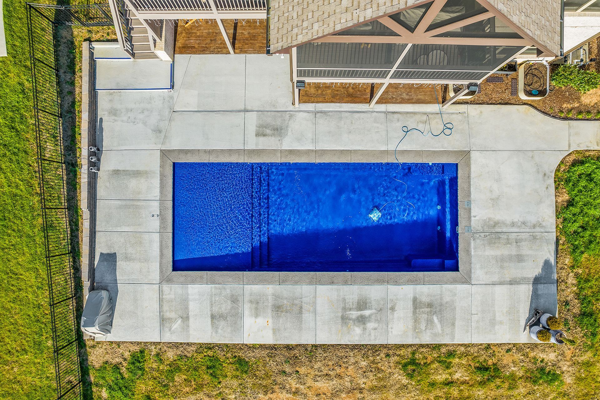 An aerial view of a large swimming pool in the backyard of a house.