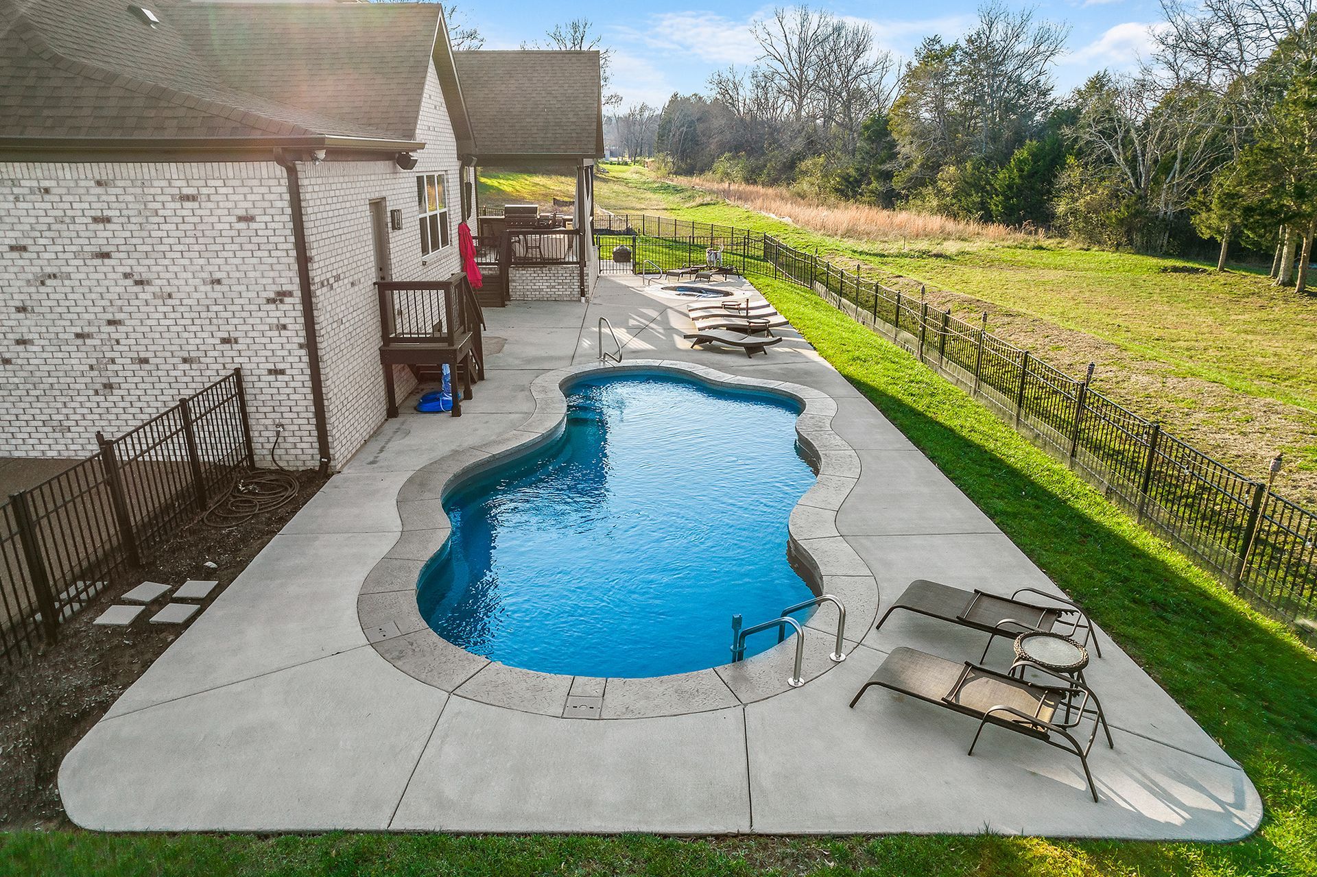 There is a large swimming pool in the backyard of a house.