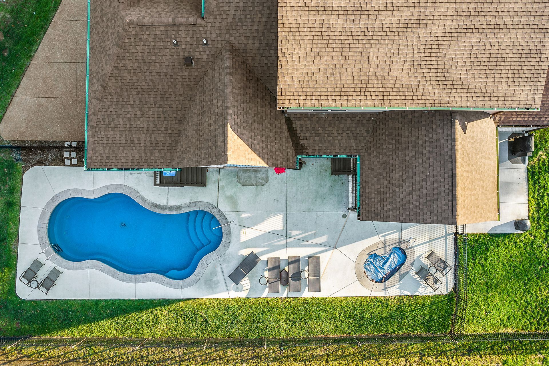 An aerial view of a house with a large swimming pool in the backyard.