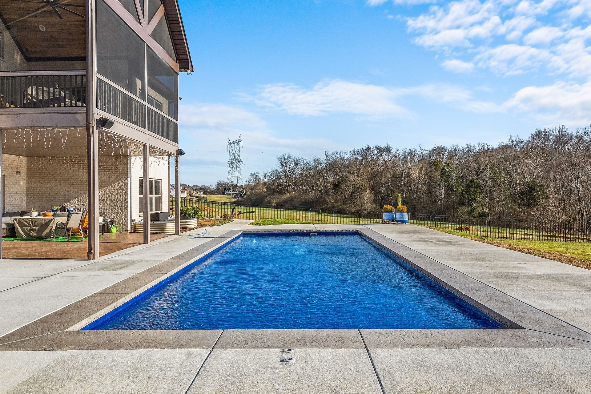 There is a large swimming pool in the backyard of a house.