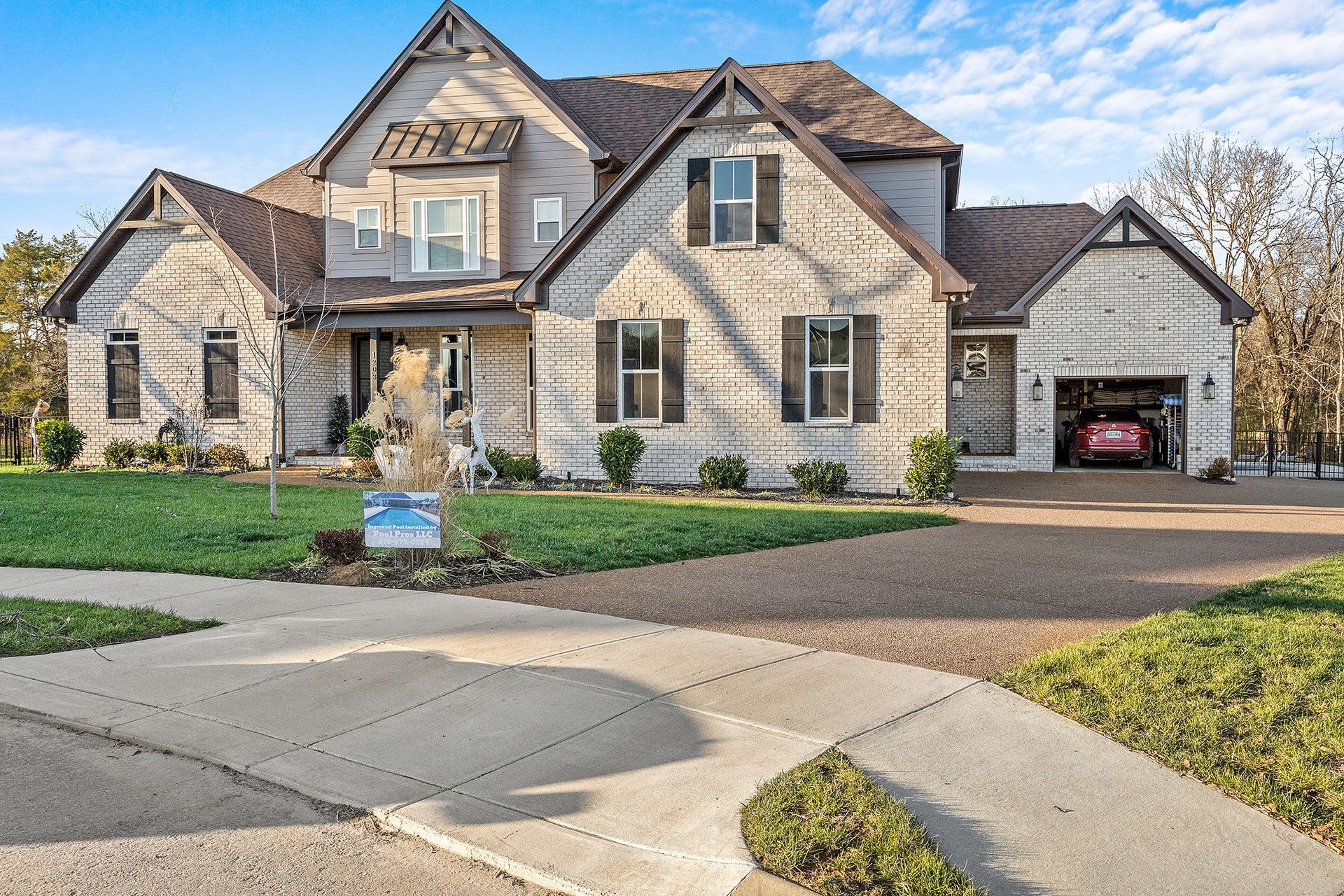A large brick house with a red car parked in the garage.