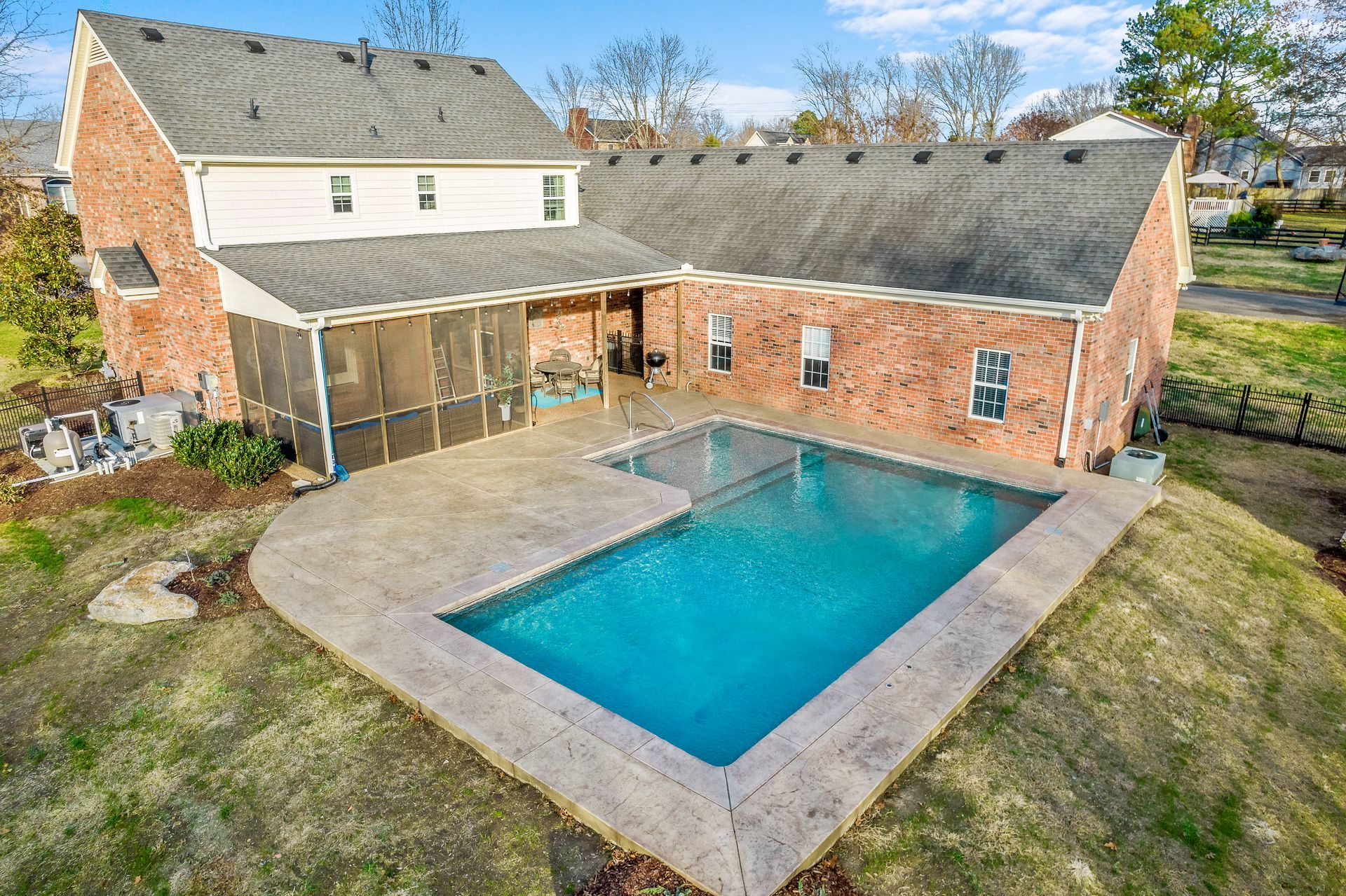 An aerial view of a house with a large swimming pool in front of it.