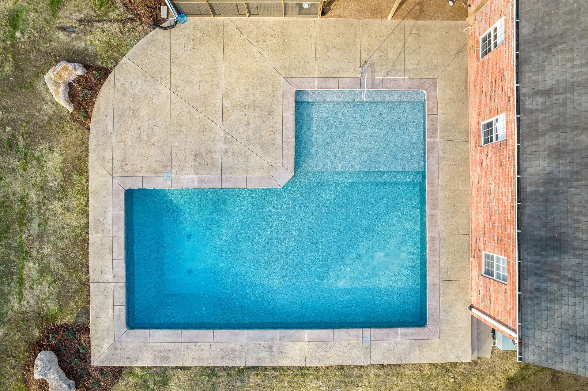 An aerial view of a large swimming pool in front of a house.