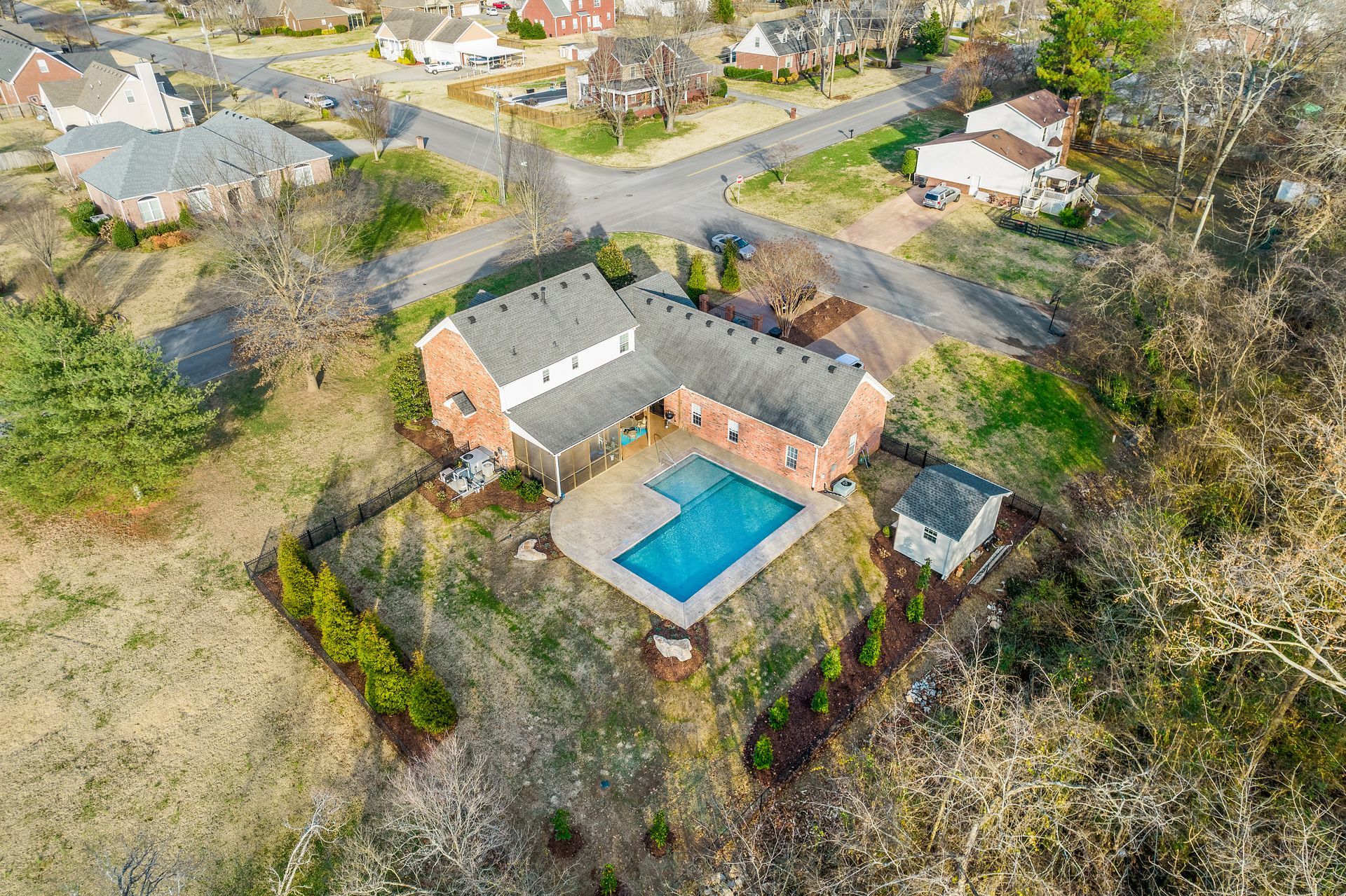An aerial view of a house with a swimming pool in a residential area.