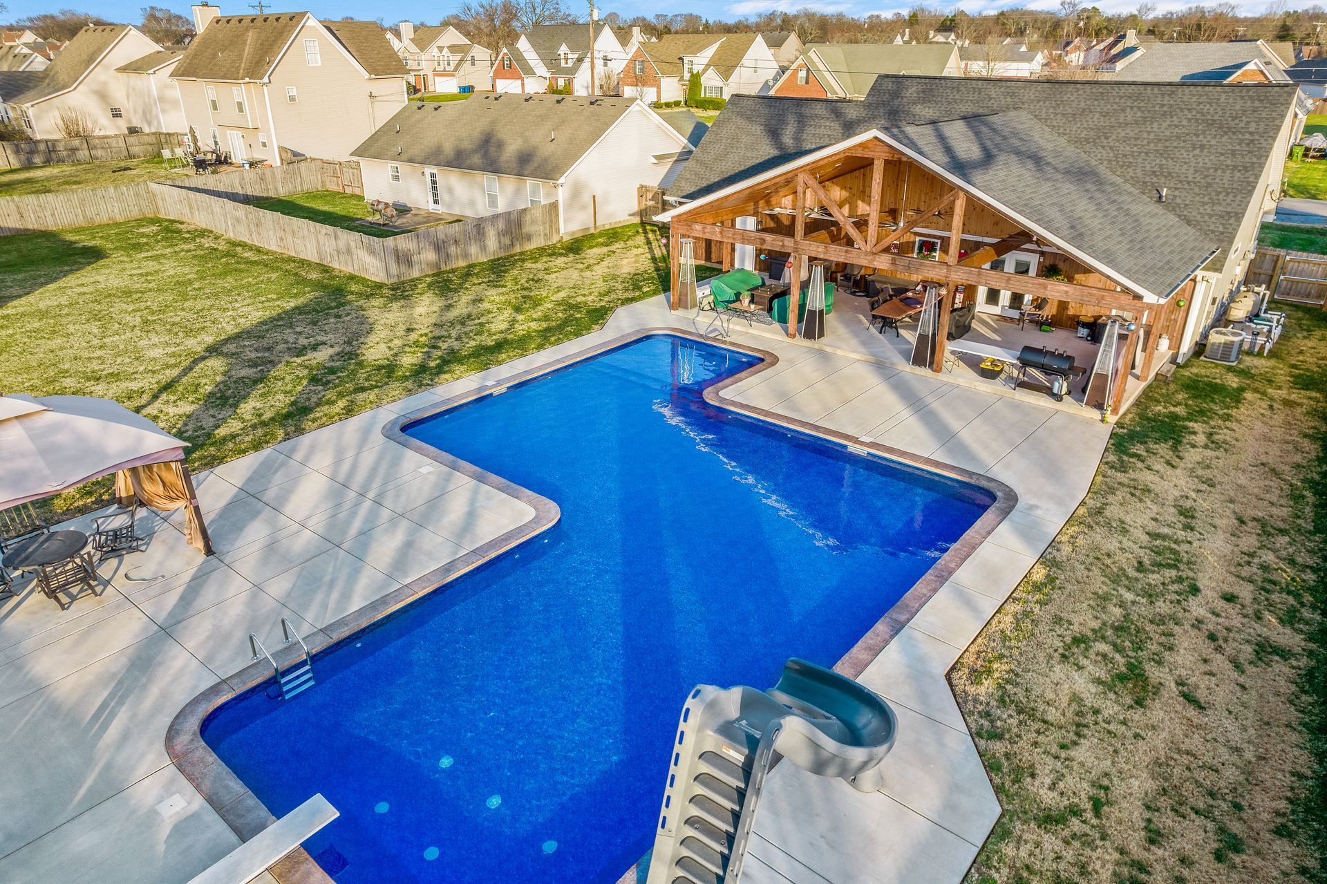 An aerial view of a large swimming pool with a slide and a house in the background.